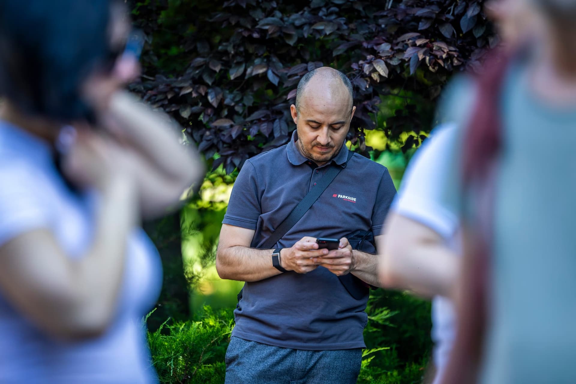 Egy TURA x Ideas Chat! résztvevő ellenőrzi a telefonját, Parkside-pólóban