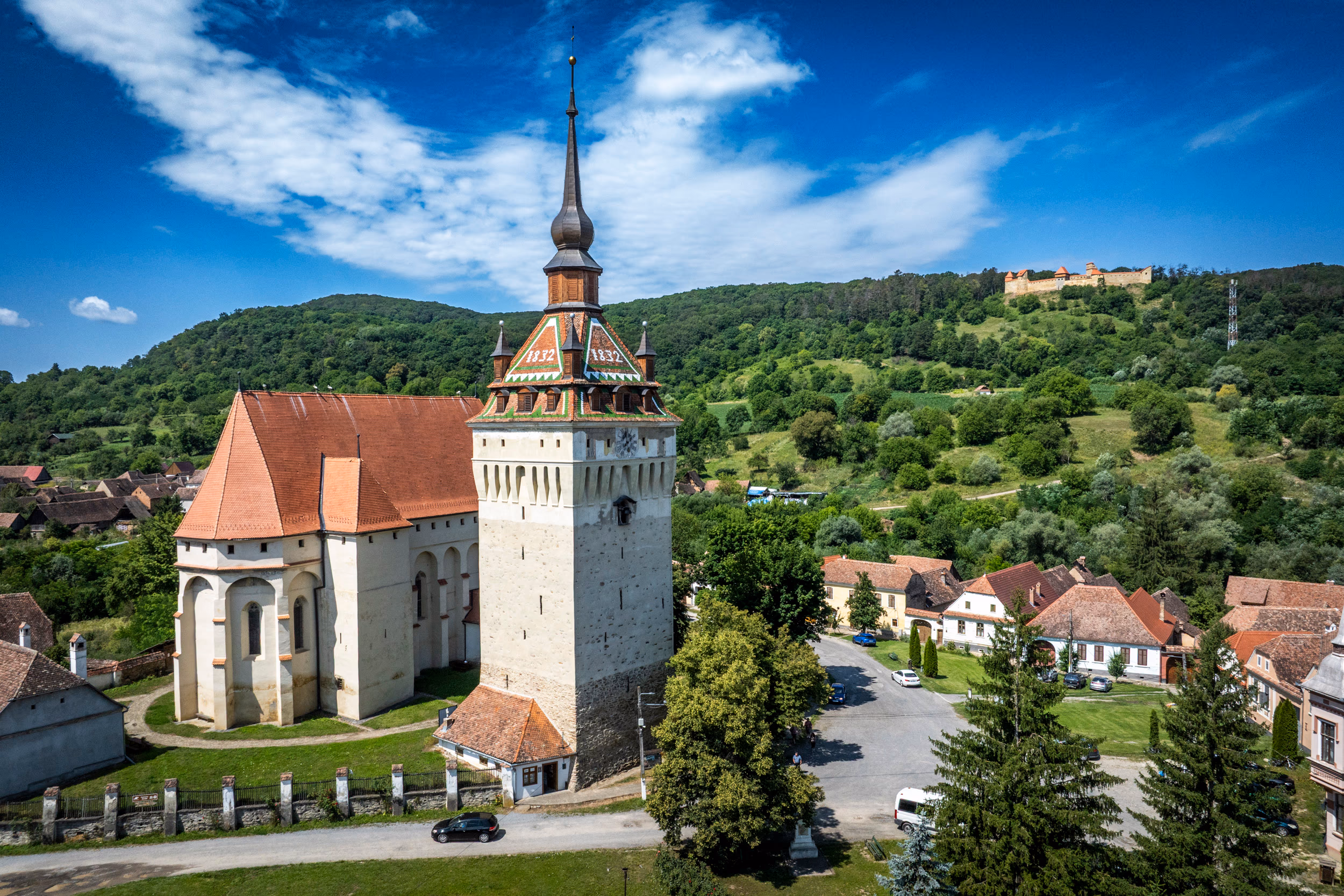 Biserica gotică, clopotnița și pe dealul din fundal silueta cetății