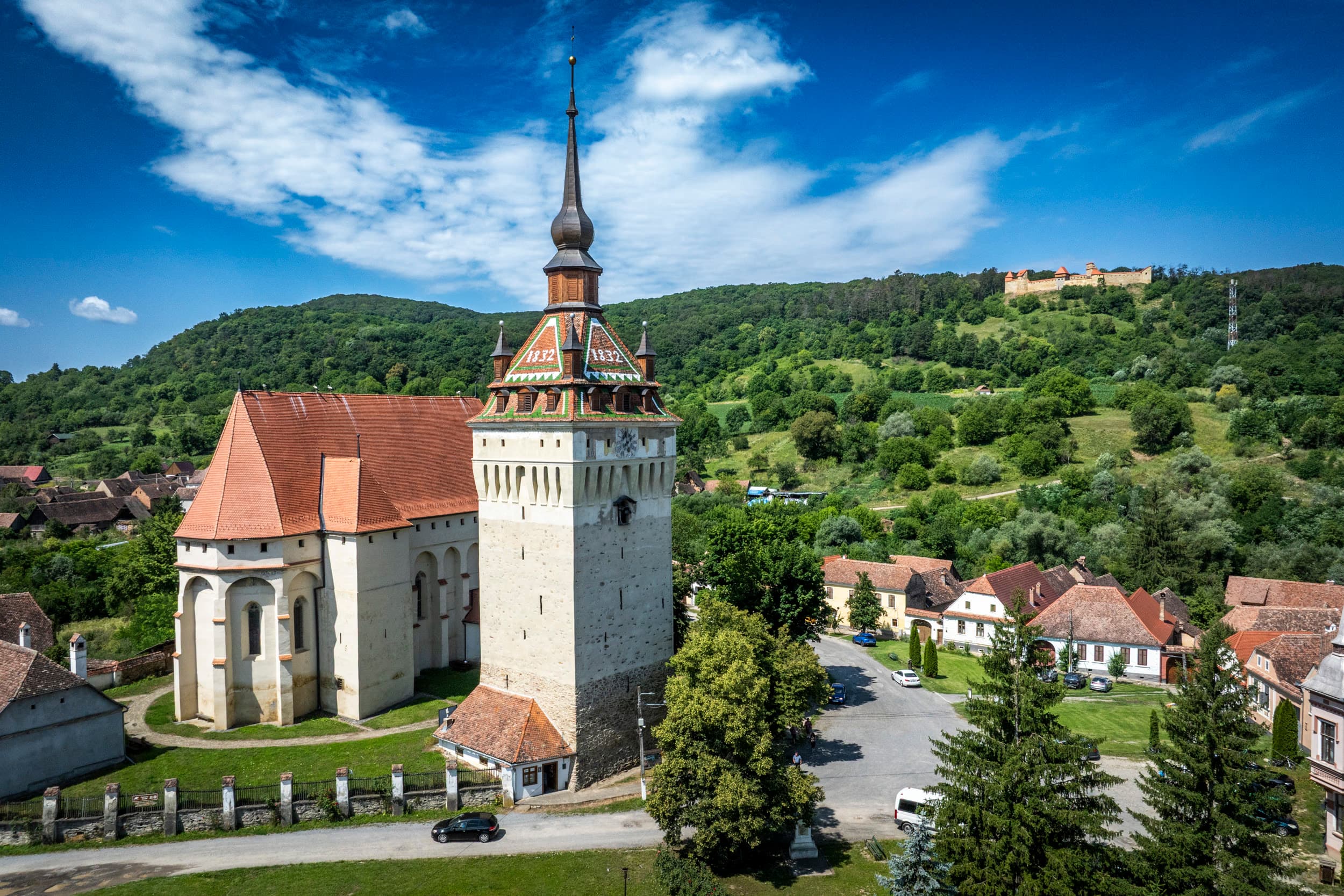 Biserica gotică, clopotnița și pe dealul din fundal silueta cetății