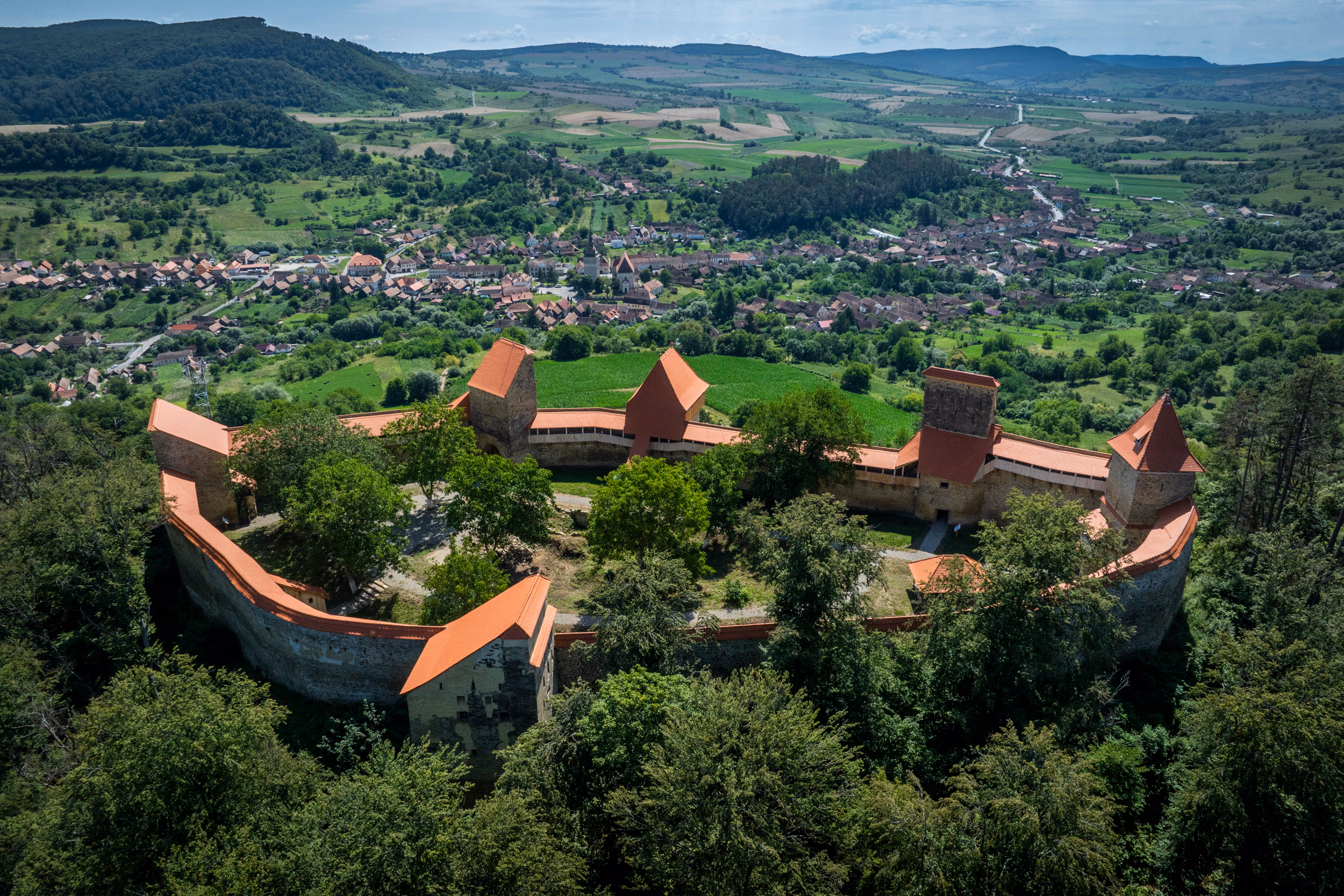 Vedere de la cetatea de pe deal — în depărtare, satul Saschiz cu biserica gotică în vatra văii