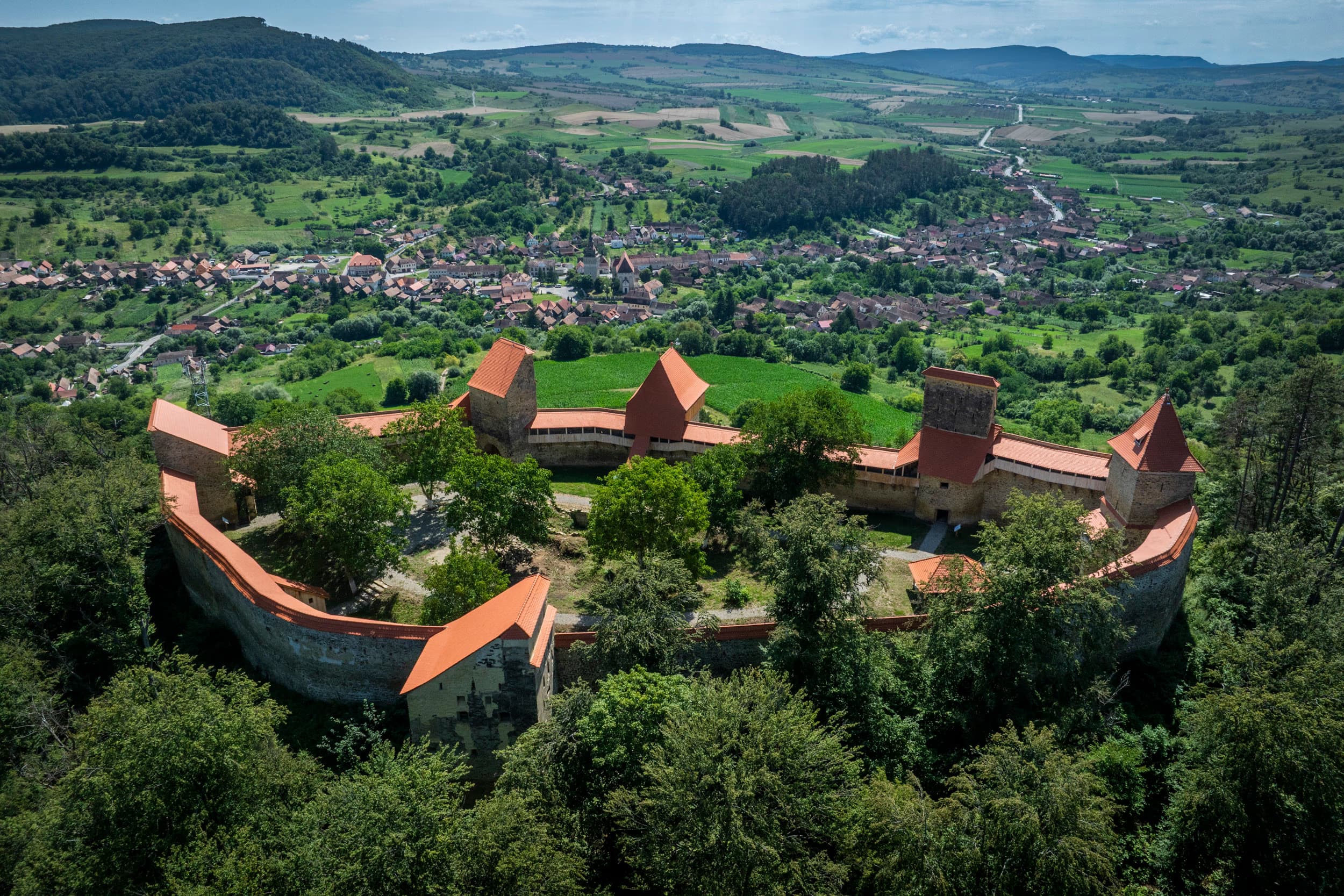 Vedere de la cetatea de pe deal — în depărtare, satul Saschiz cu biserica gotică în vatra văii