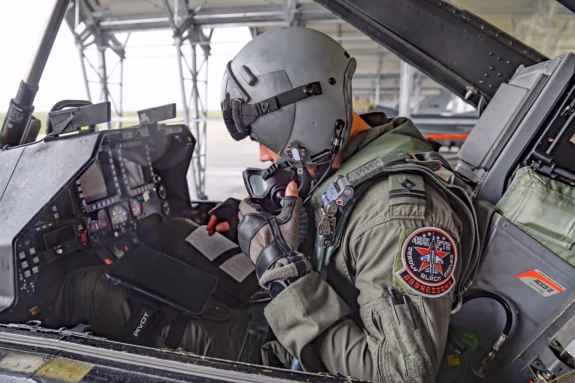 Aggressor pilóta egy F-16 pilótafülkéjében — oxigénmaszkkal és a 435 Black Aggressors emblémájával