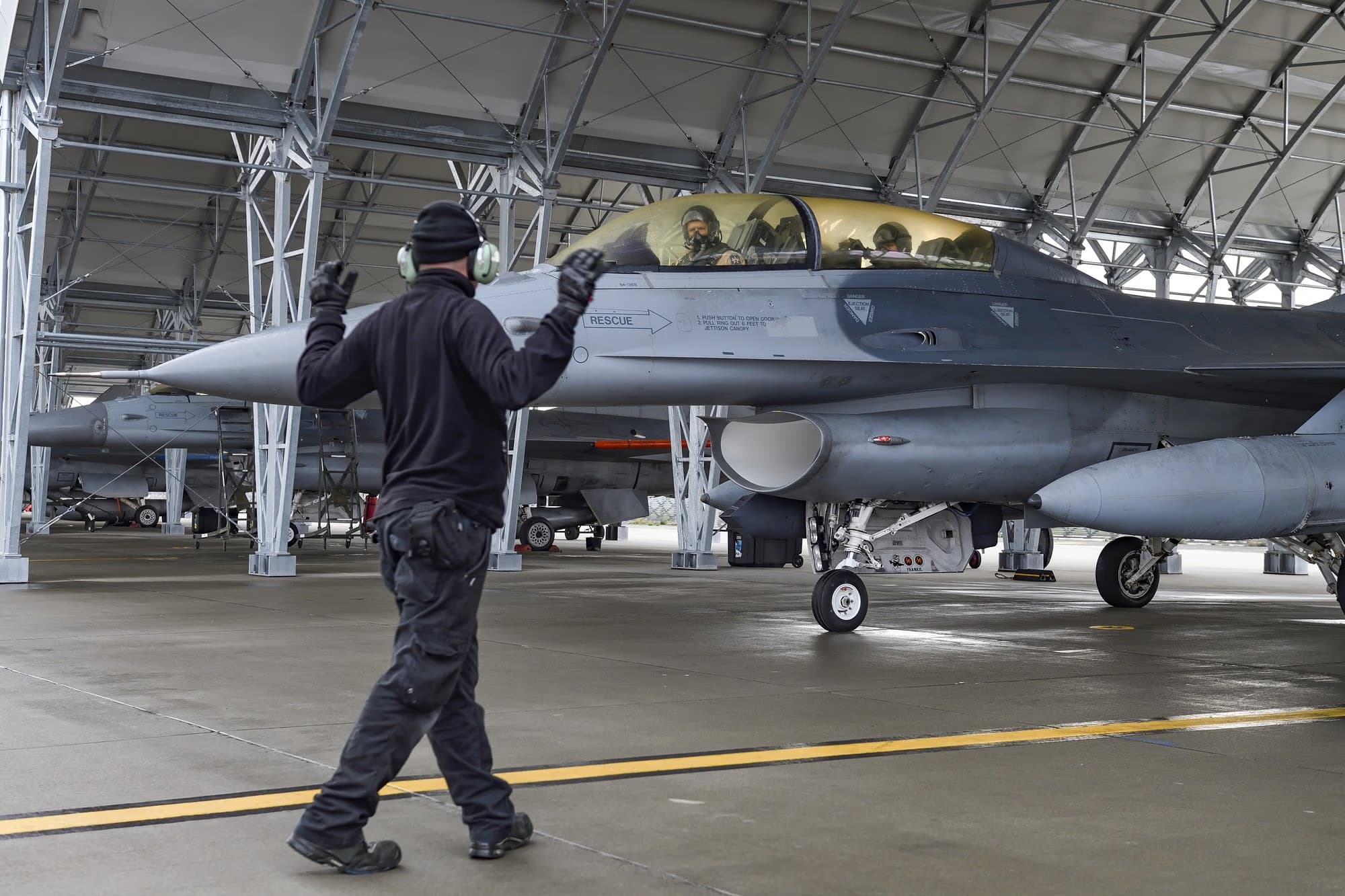 Földi technikus irányít egy F-16-ost a Fetești-i Európai F-16 Kiképzőközpont hangárjában