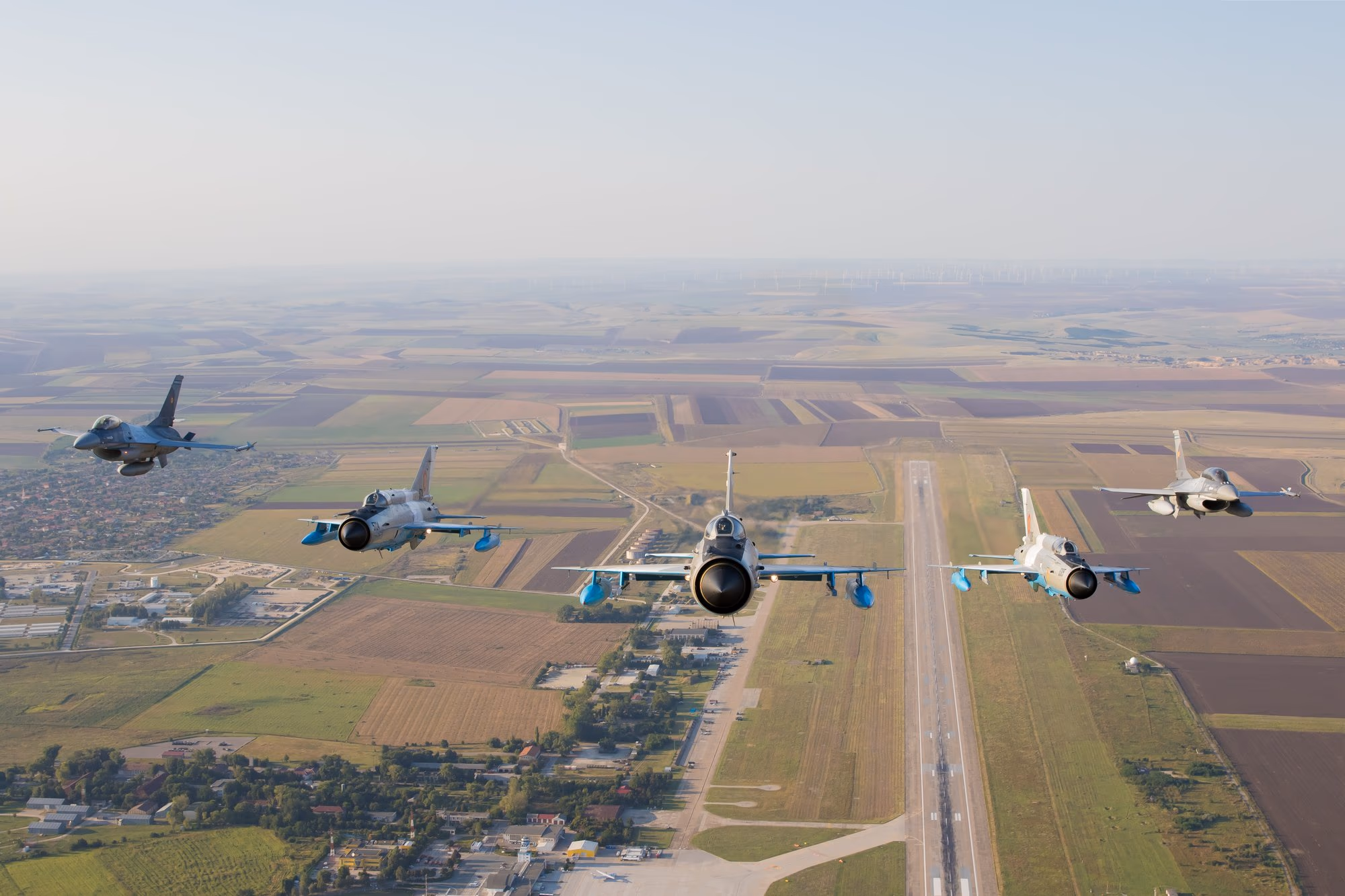 Öt román légierős F-16-os formációban repül egy leszállópálya felett, manőverezés közben