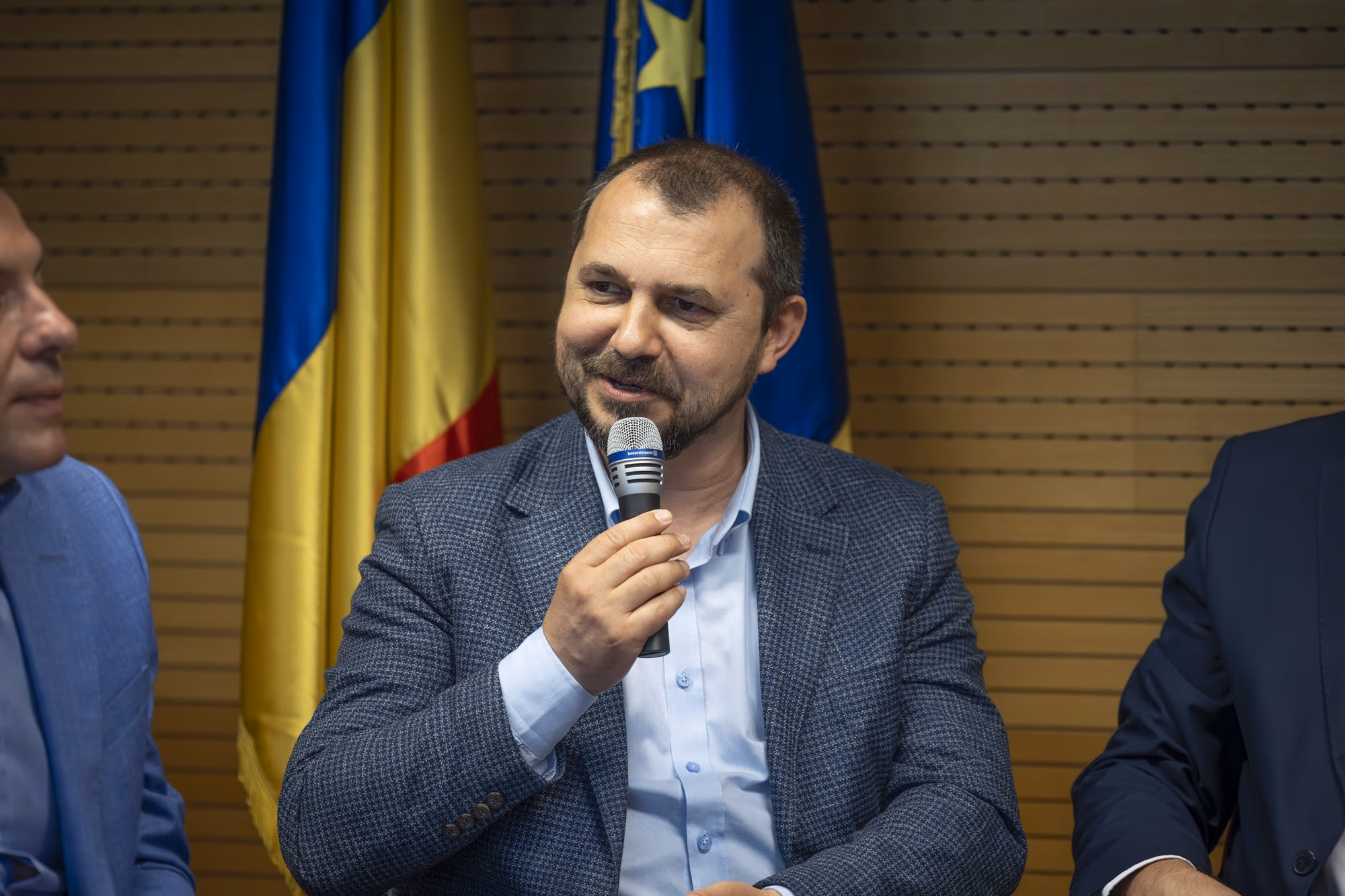 Mircea Șcheau, president of the Cloud Security Alliance Romania Chapter, smiling at the microphone, grey houndstooth blazer