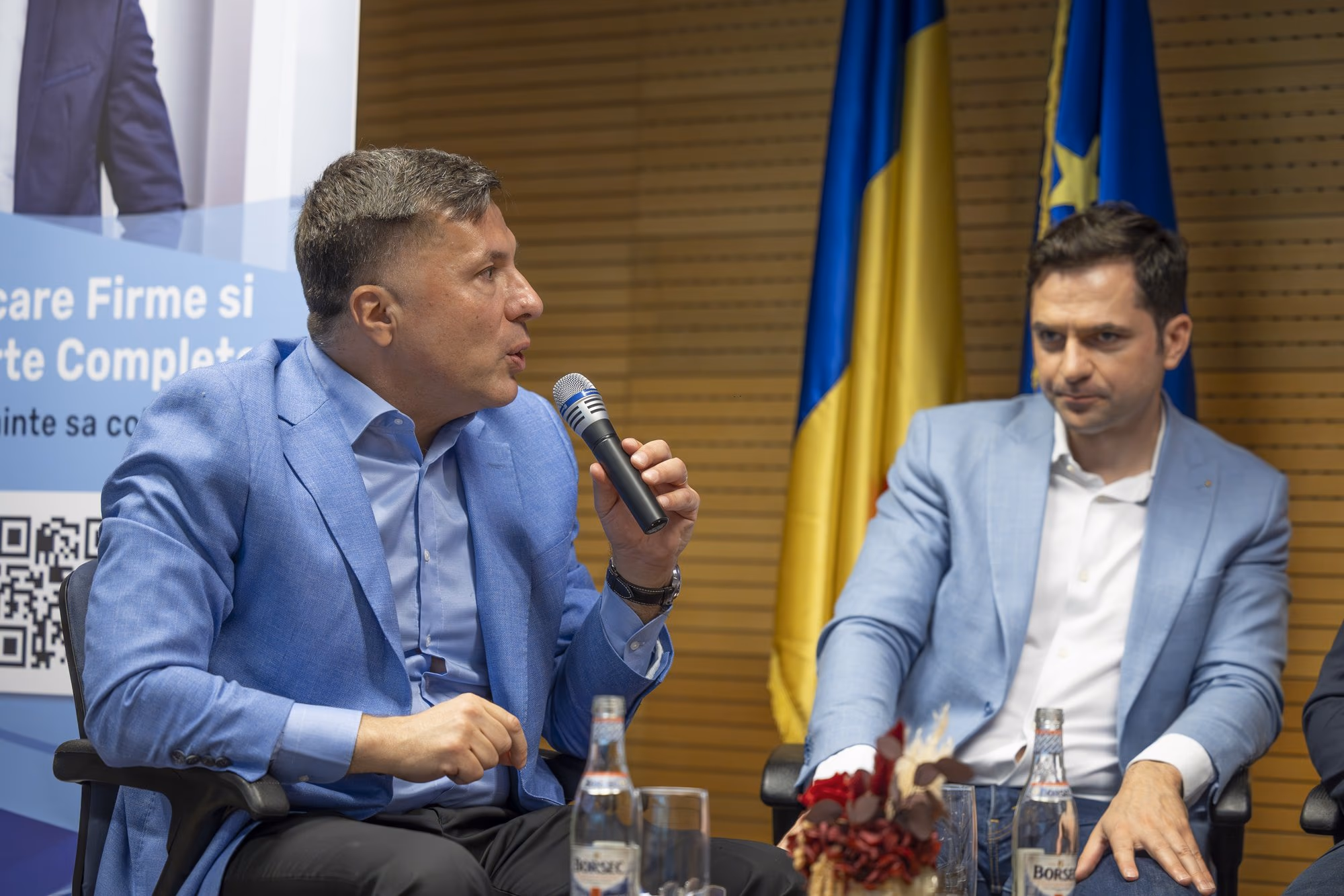 Sebastian Burduja and Bogdan Putinică in side dialogue on stage