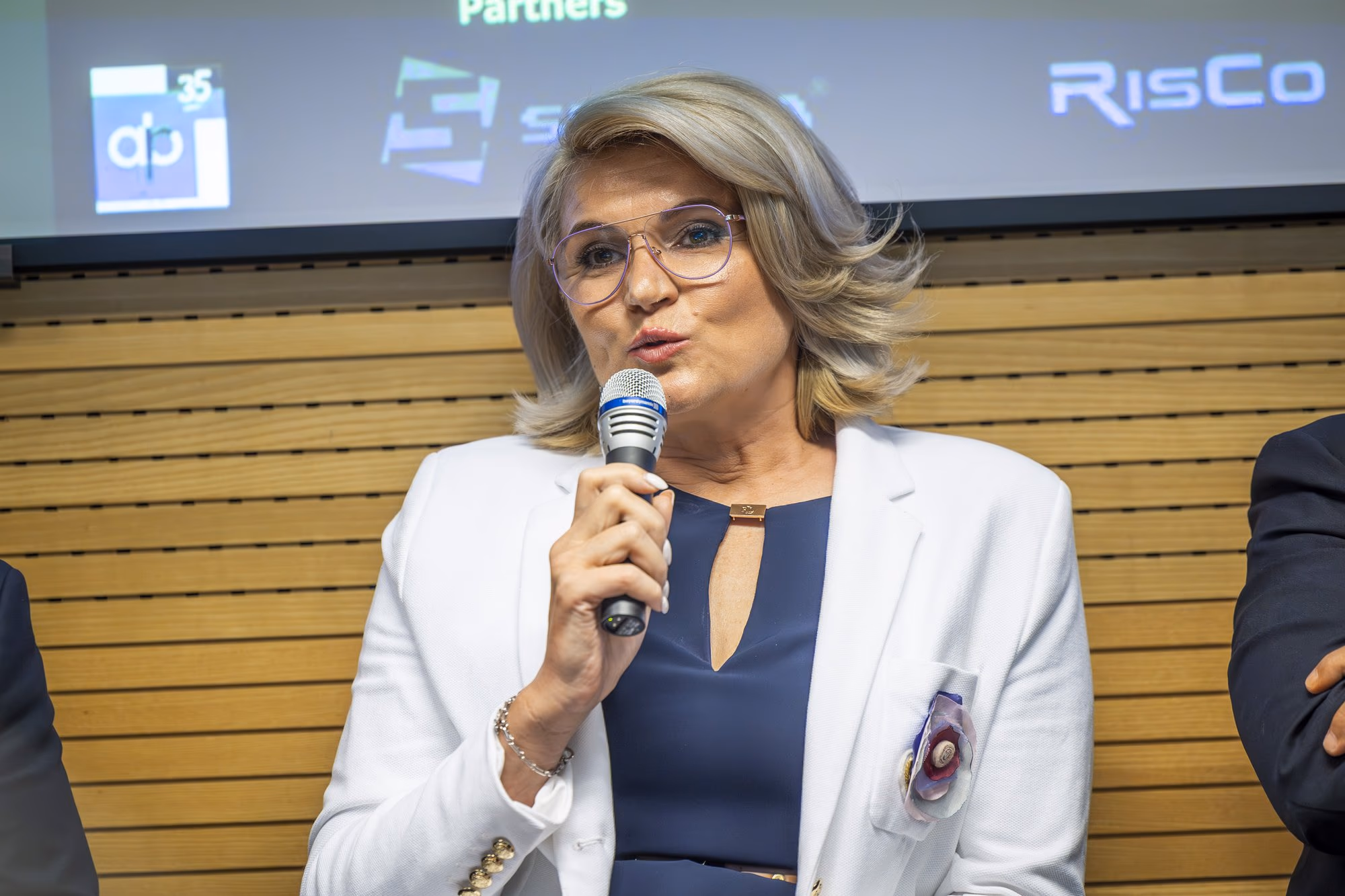 Andreea Paul, ASE lecturer and INACO president, speaking into the microphone with animated expression