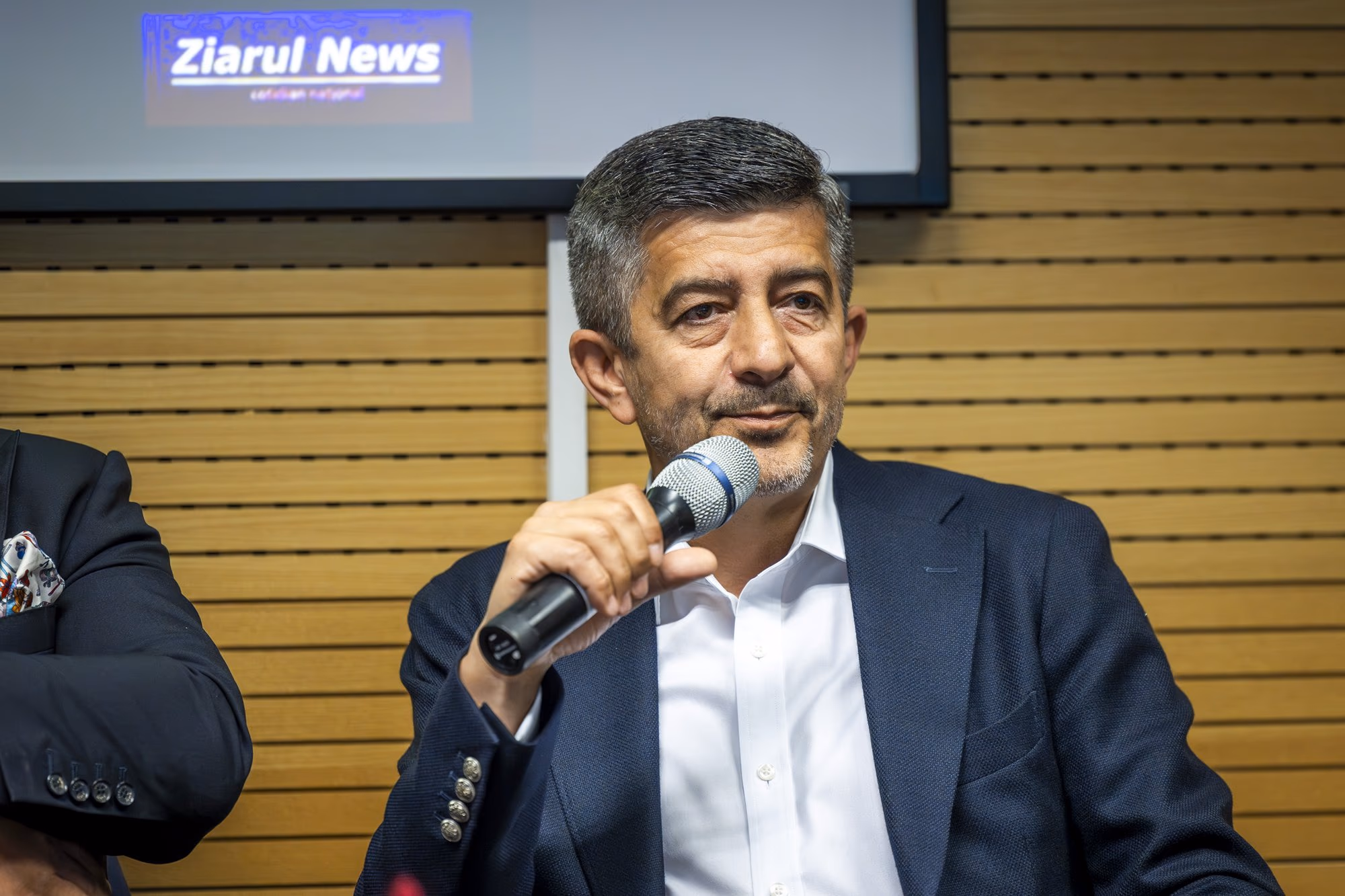 Florian Libocor, chief economist at BRD, speaking into the microphone, navy suit, no glasses