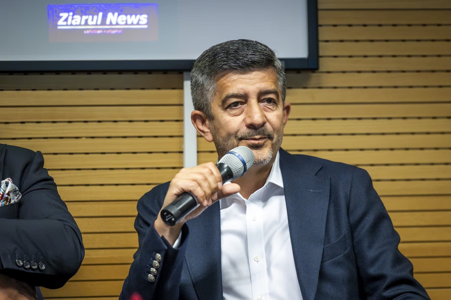 Florian Libocor, economist-șef la BRD, vorbind la microfon, costum bleumarin, fără ochelari