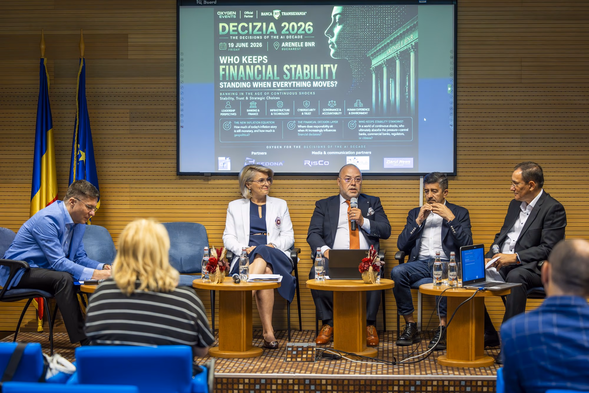 „Who Keeps Financial Stability Standing When Everything Moves" panel — five panellists on stage, screen with the title behind them