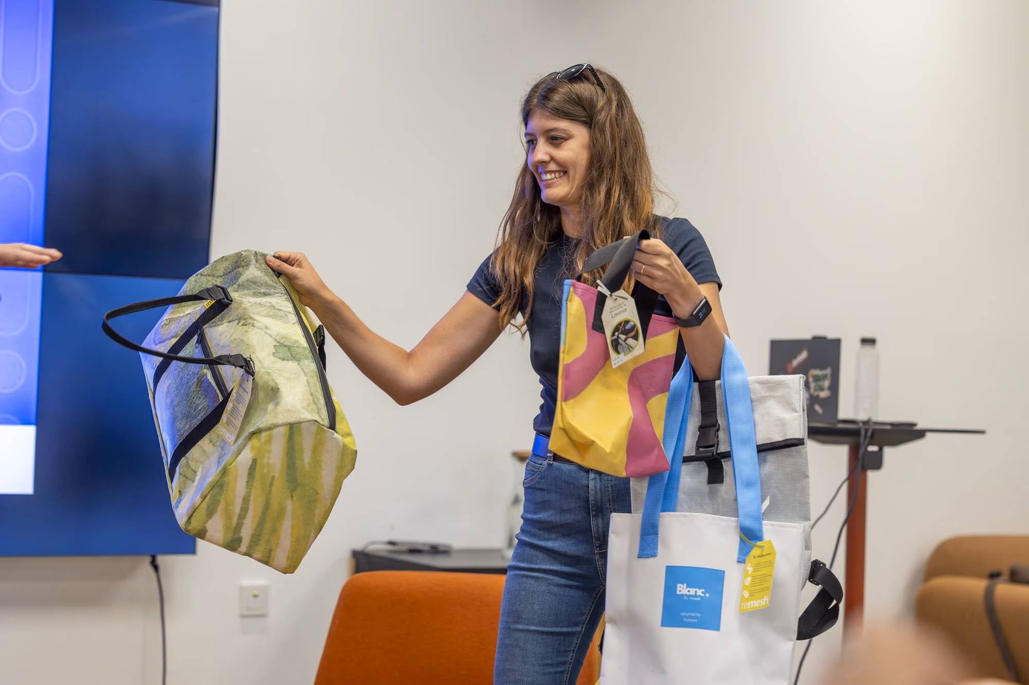 A representative from Ateliere Fără Frontiere demonstrating bags made from recycled street banners, the Remesh brand.