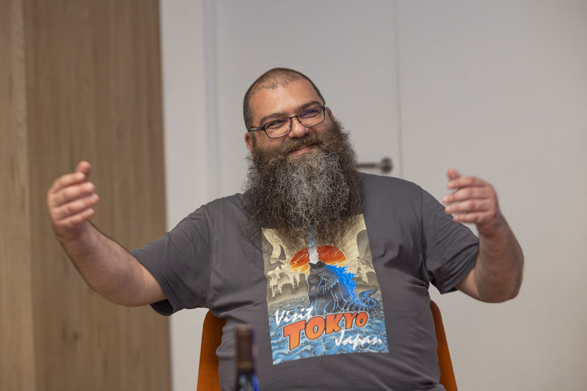 Andrei Pogăciaș, doctor of military history, with a long beard and a "Visit Tokyo" T-shirt, at the microphone.