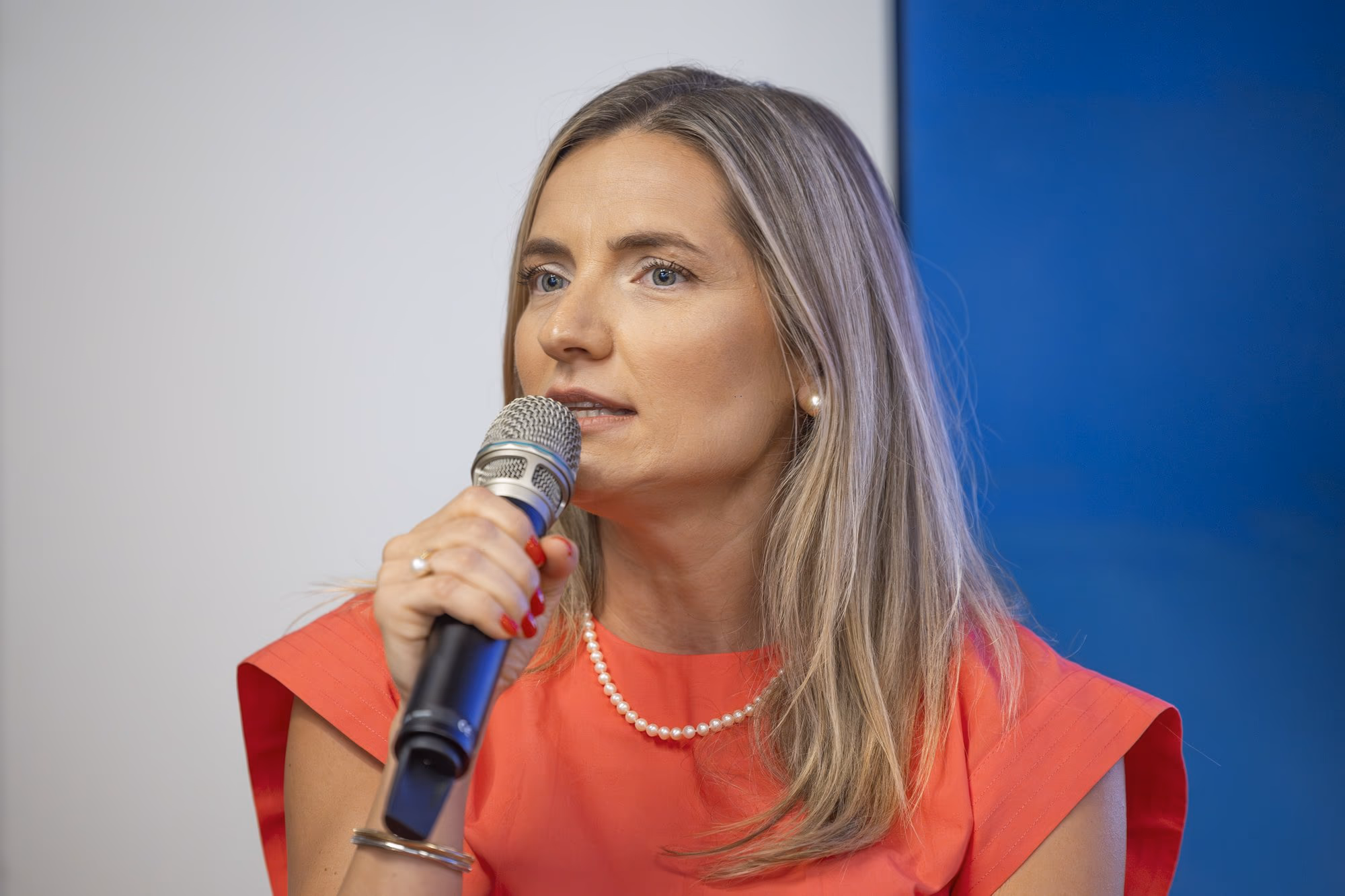 Manuela Ciugudean, brand strategist, in a red dress, at the microphone in panel 3.