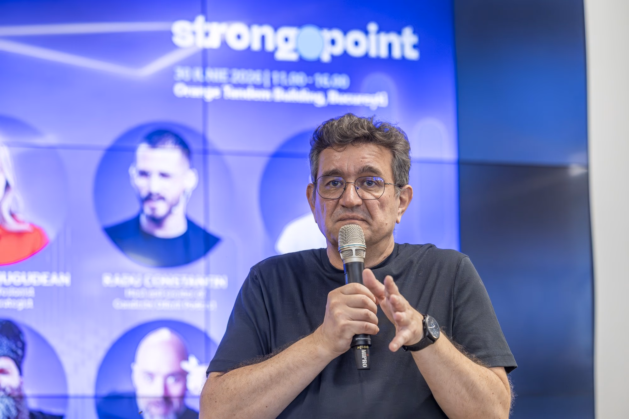 Chinezu a mikrofonnál, az 1. panelben — a moderátor, aki stand-up színészként vezet.