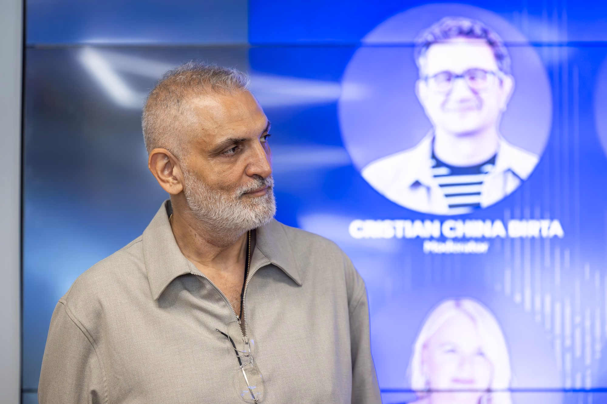 Damian Drăghici in profile, with his poster photo in the background.