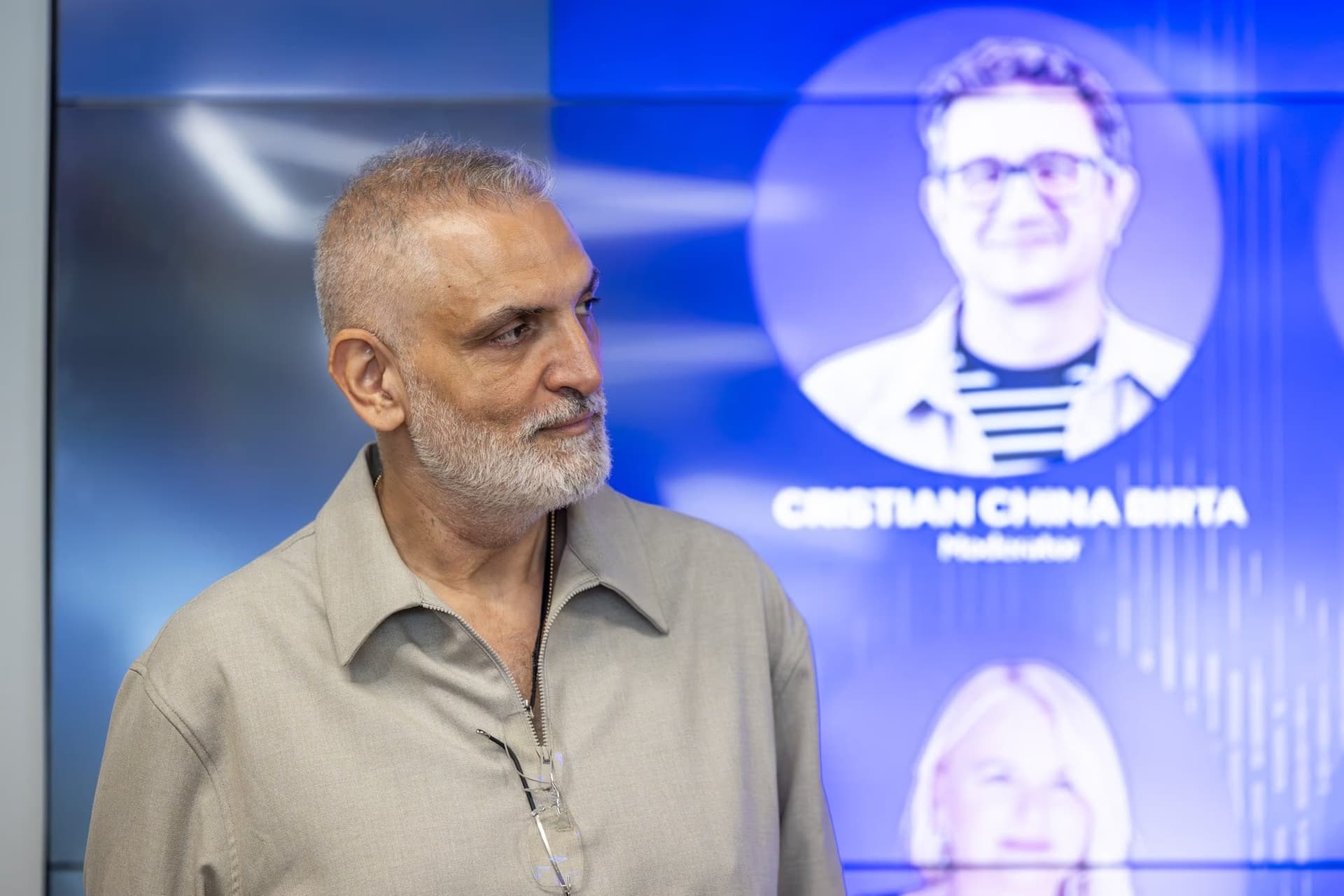 Damian Drăghici profilban, a plakát fotójával a hátterében.
