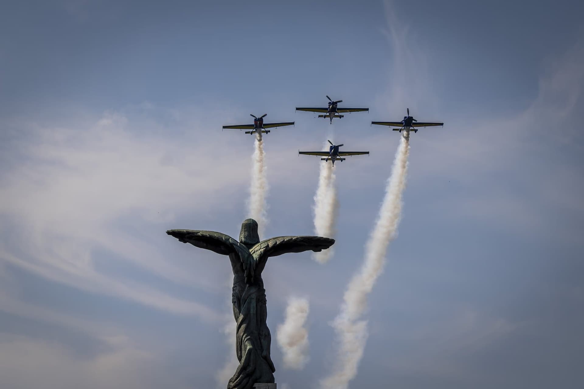 The Extra 300 formation of the Romanian Aeroclub, trailing white smoke above the Monument of the Heroes of the Air. Photo: AdiCoco.com