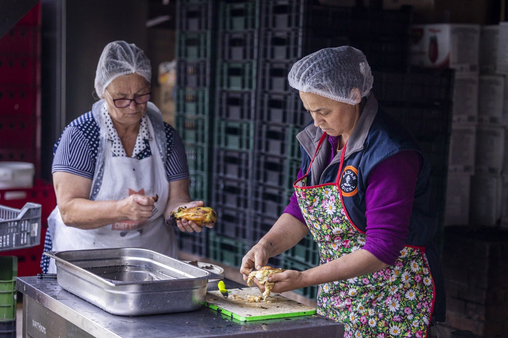 Women peeling the roasted aubergines at the stainless-steel table