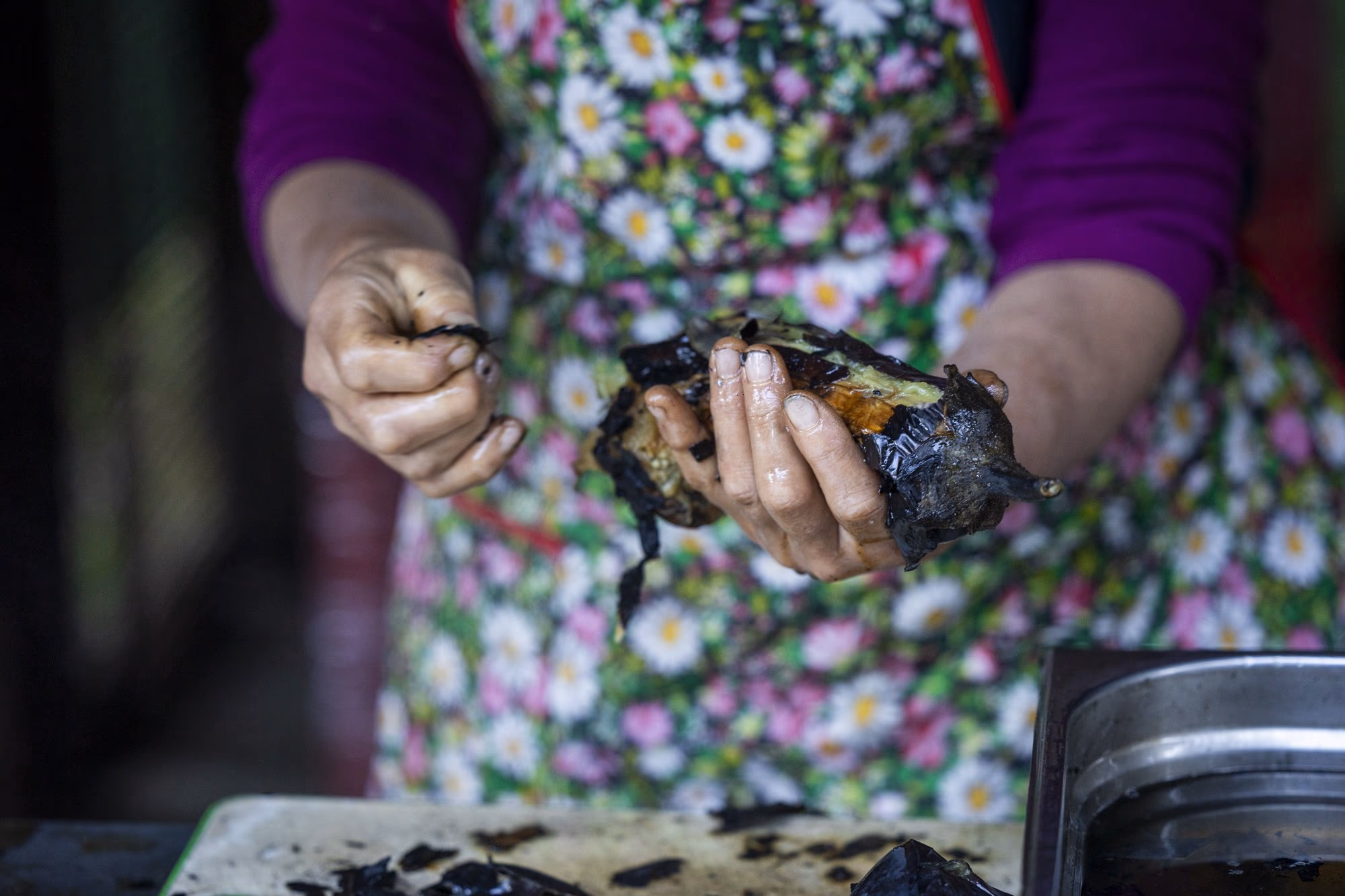 Hands peeling a roasted aubergine