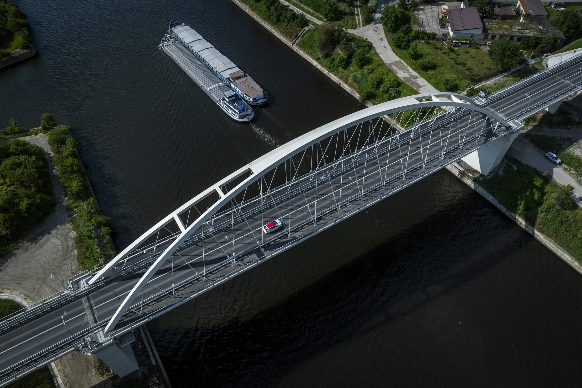 The deck from above: a red car on the bridge, a long barge on the canal