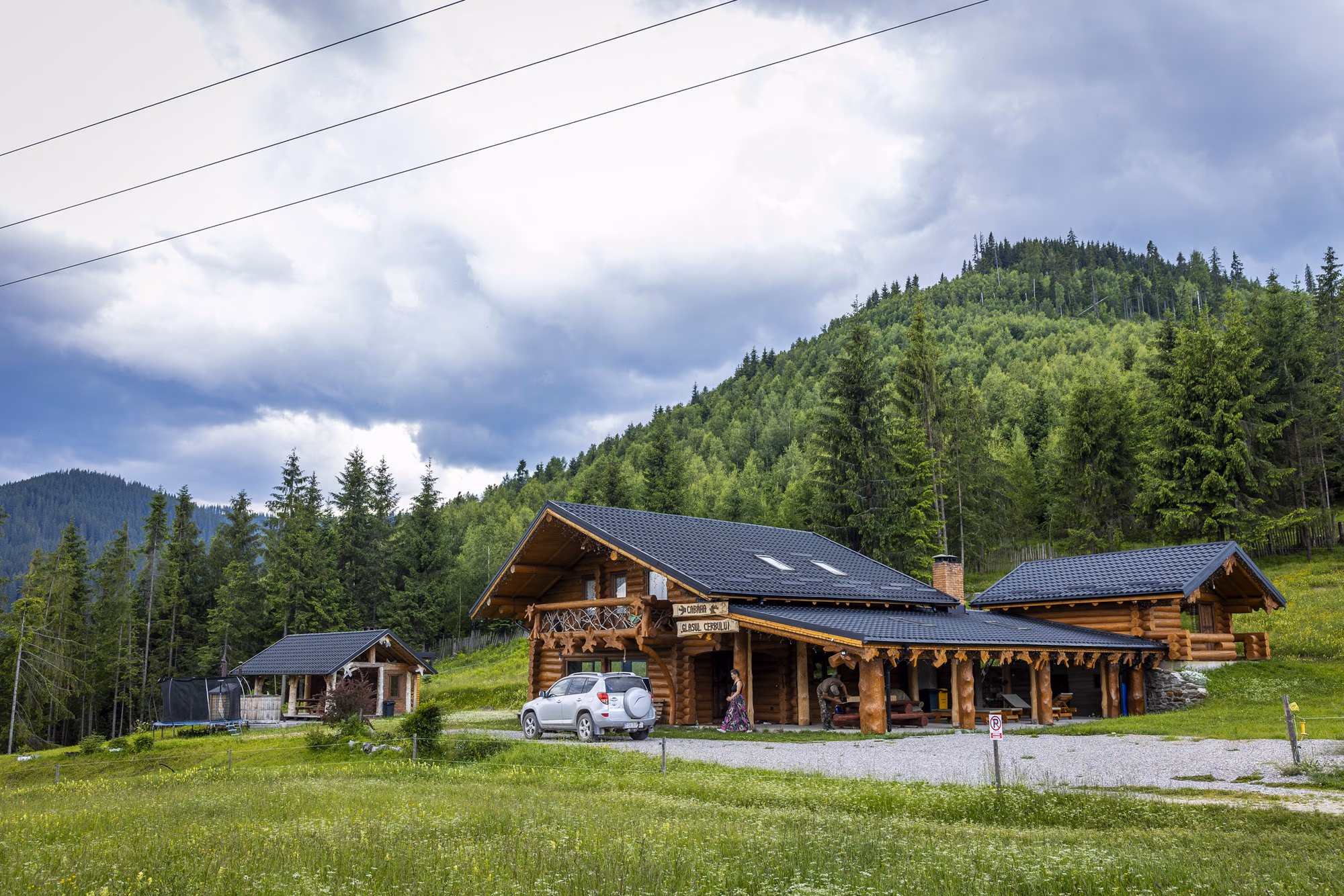 Cabana de bârne de la intrare, cu terasa și parcarea