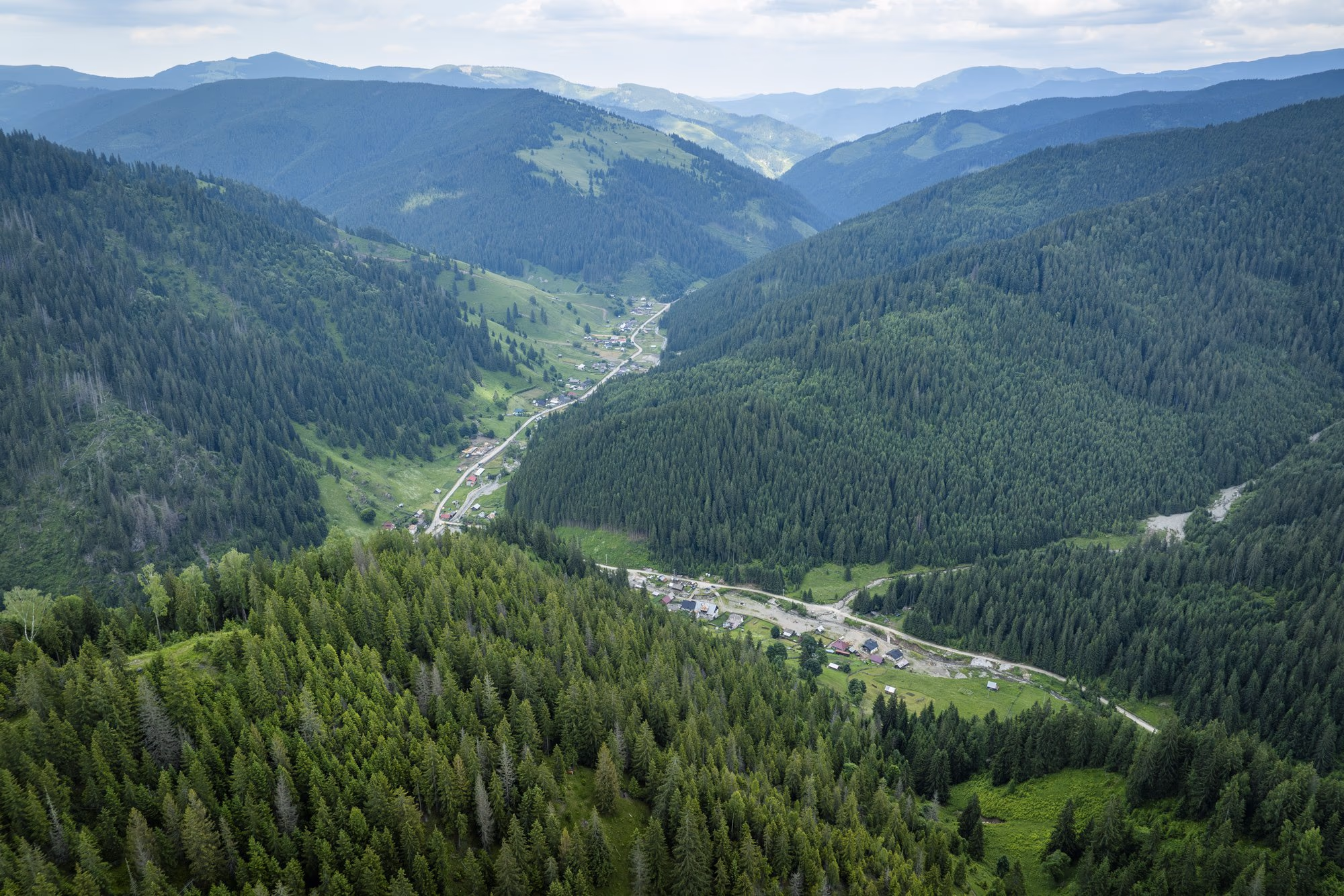 Valea cu satul risipit pe firul apei, văzută din dronă