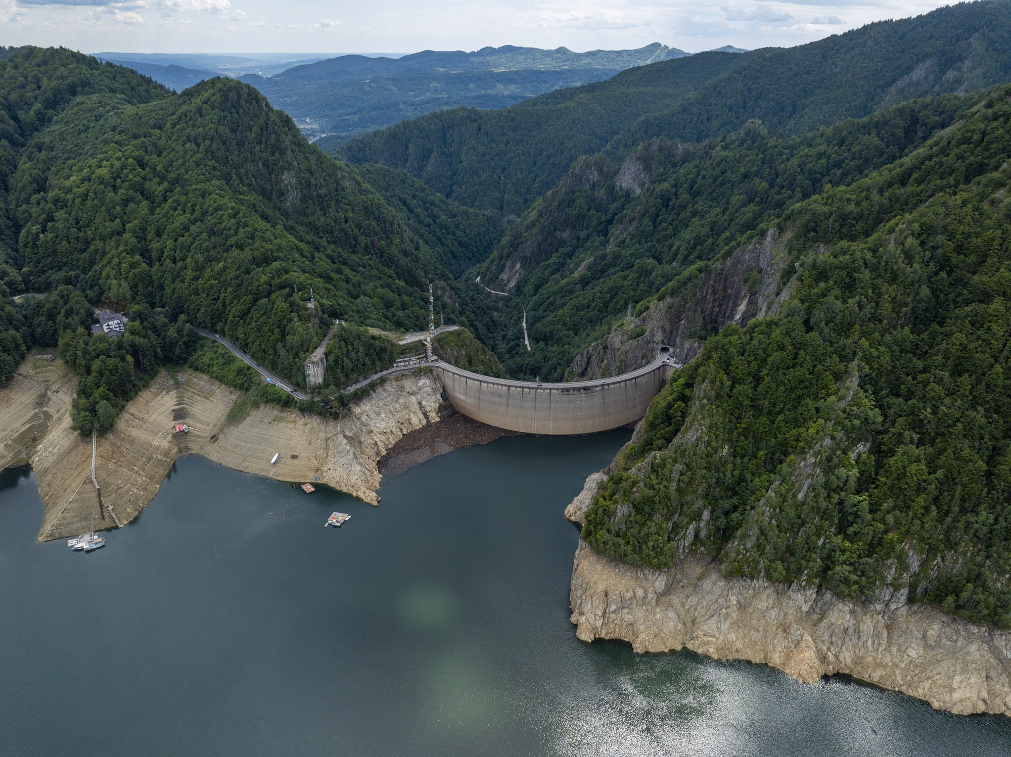 The Vidraru dam seen from a drone, the reservoir refilling and the exposed bathtub ring along the shore