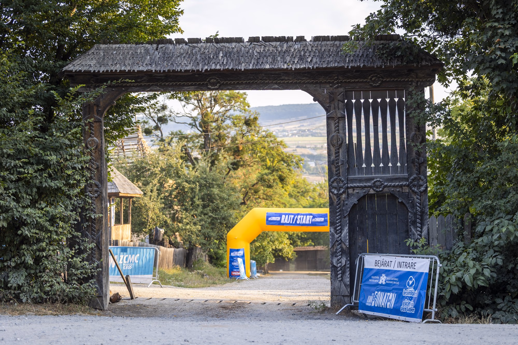 Poarta de lemn a Parcului Etnografic Romulus Vuia din Cluj, dimineața, cu arcada gonflabilă de start a crosului în spate