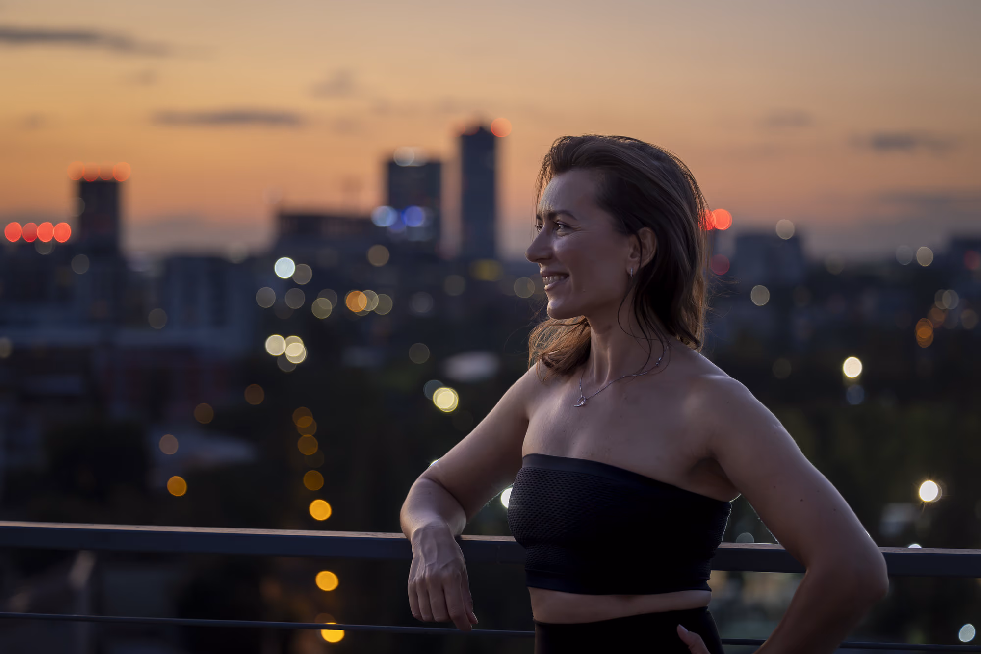Portret al Ancăi Iftime la apus, cu luminile orașului aprinse în fundal