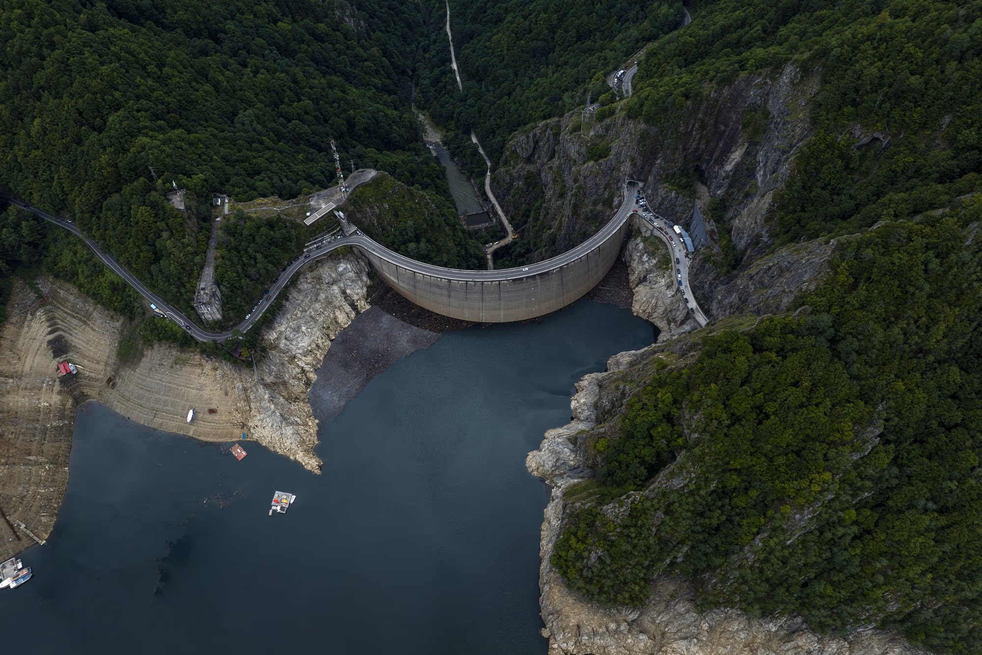 Vidraru dam seen from above, with the reservoir almost empty behind it