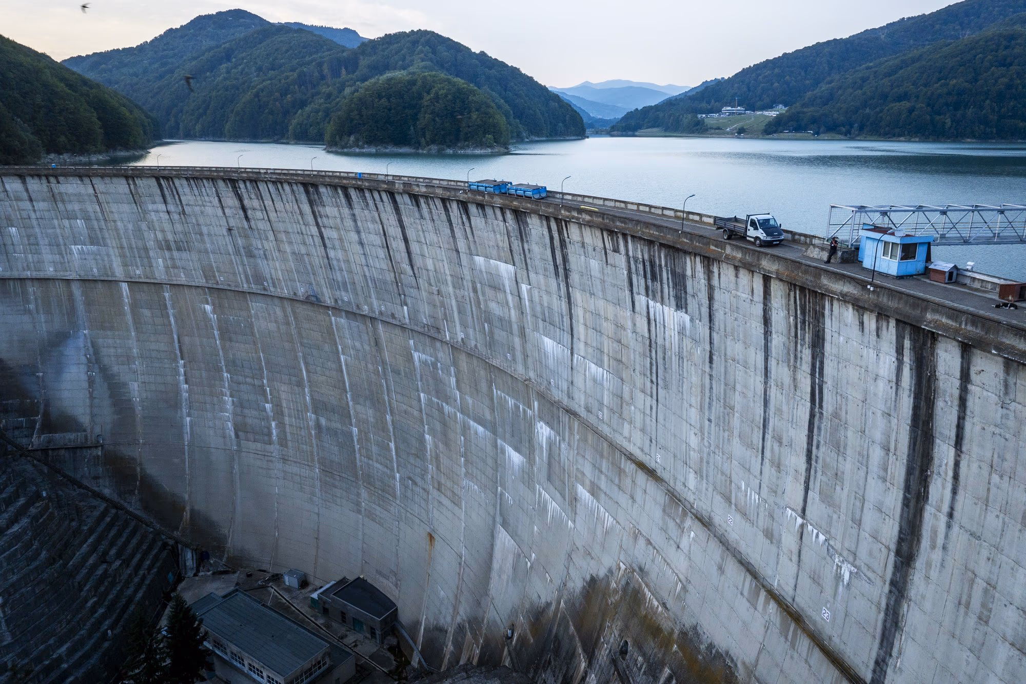 The curved face of Paltinu dam, with the Doftana reservoir behind, in evening light