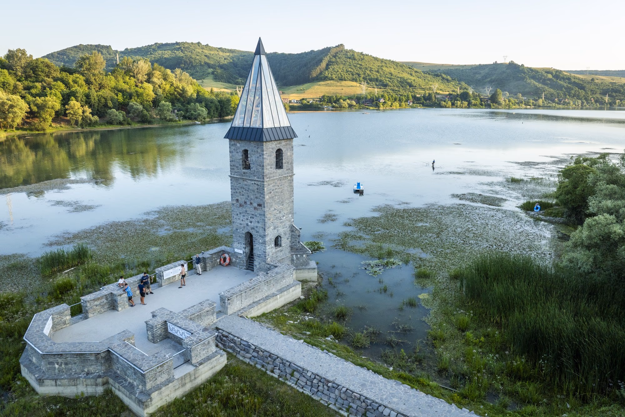 The tower of the "Church of Solidarity" at Bezid, raised on piles in the lake, with its access causeway and people on the platform