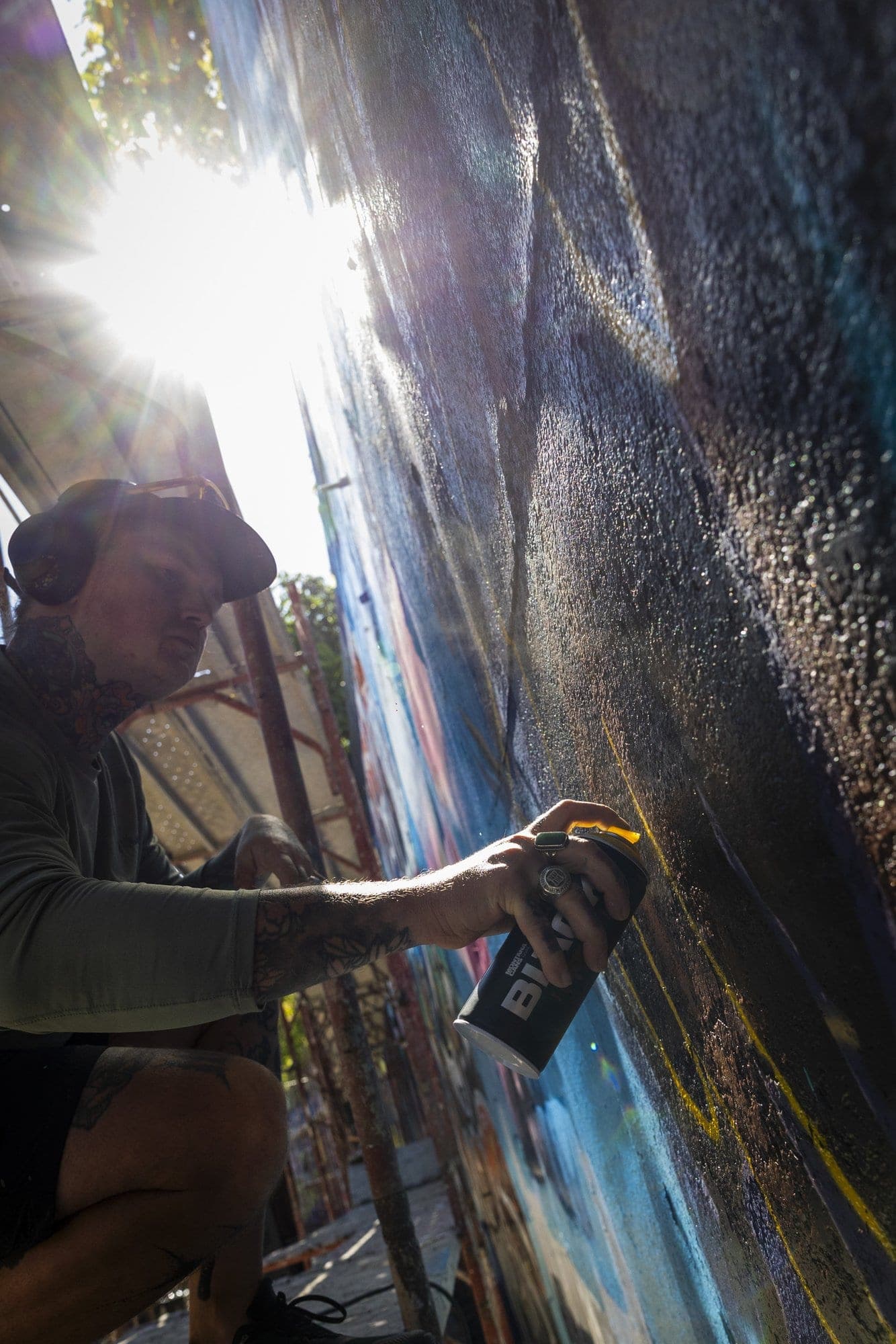 Artist ghemuit la perete, cu soarele intrând direct peste zid și spărgându-se în lumină