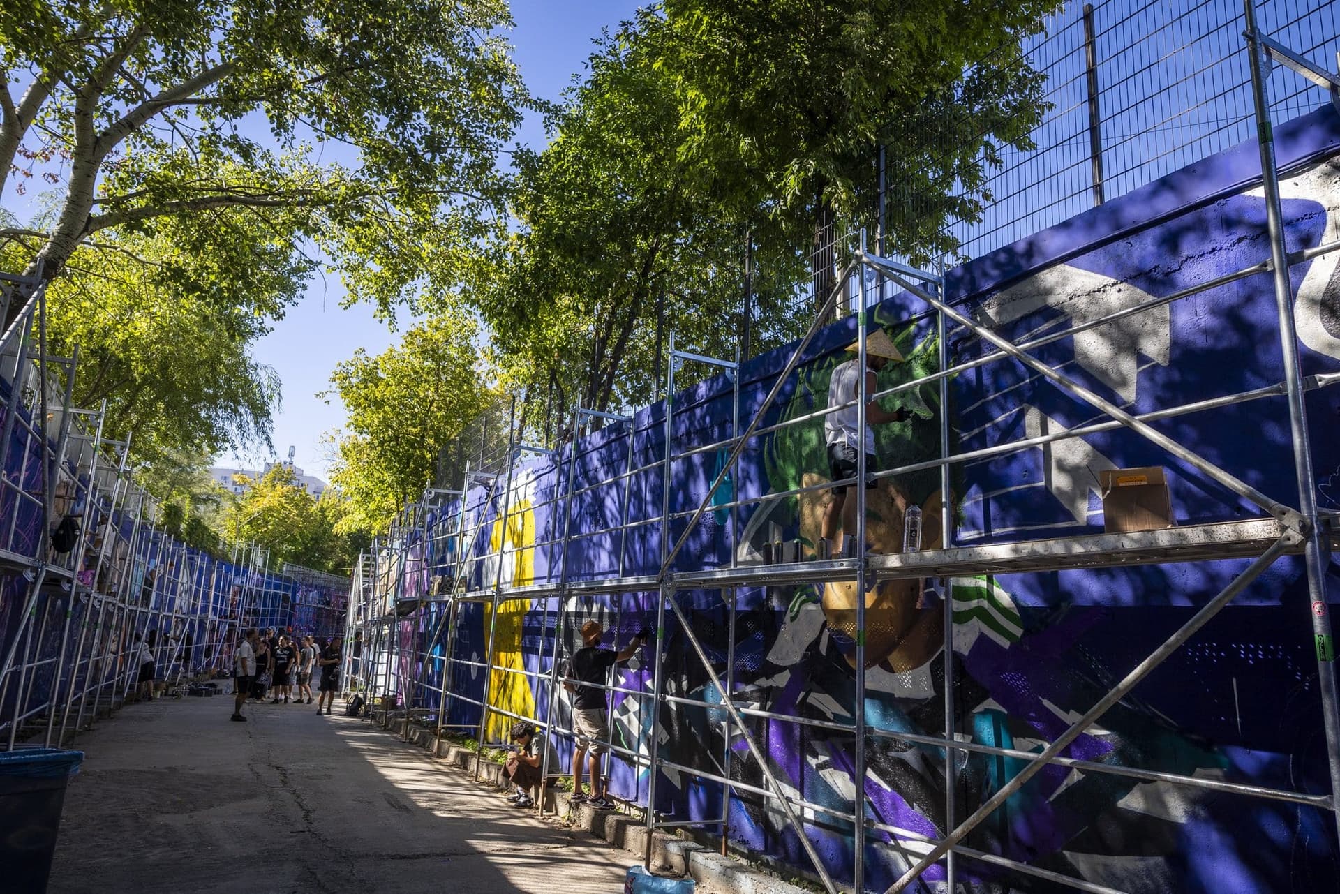 Porțiunea descoperită a pasajului feroviar de sub Lujerului, cu peretele albastru încă vizibil între lucrări, schele montate pe toată lungimea și copaci deasupra