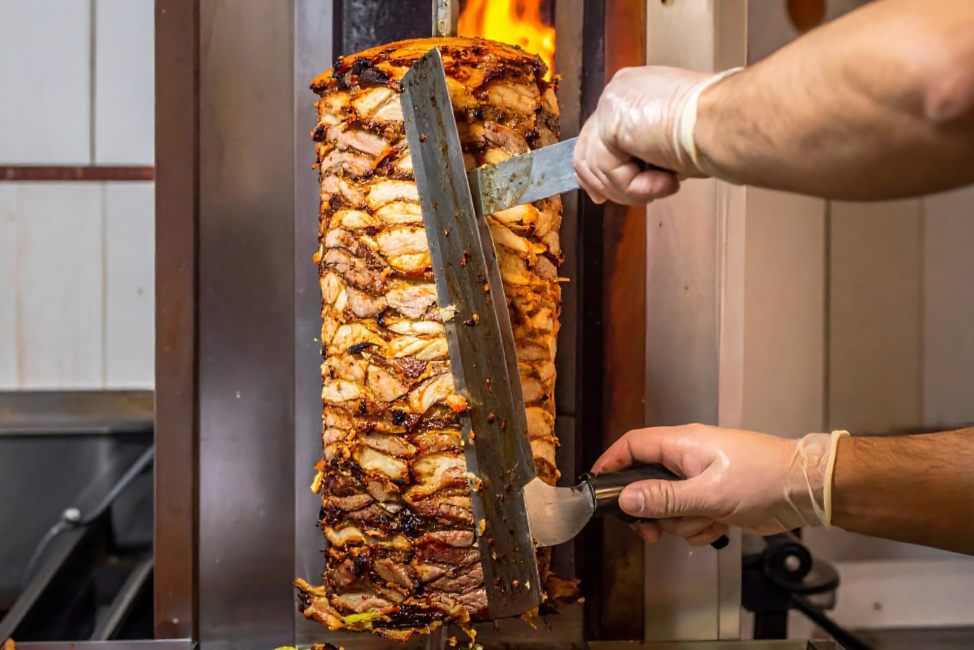 Carne de shaorma pe rotisorul vertical, tăiată cu cuțitul lung