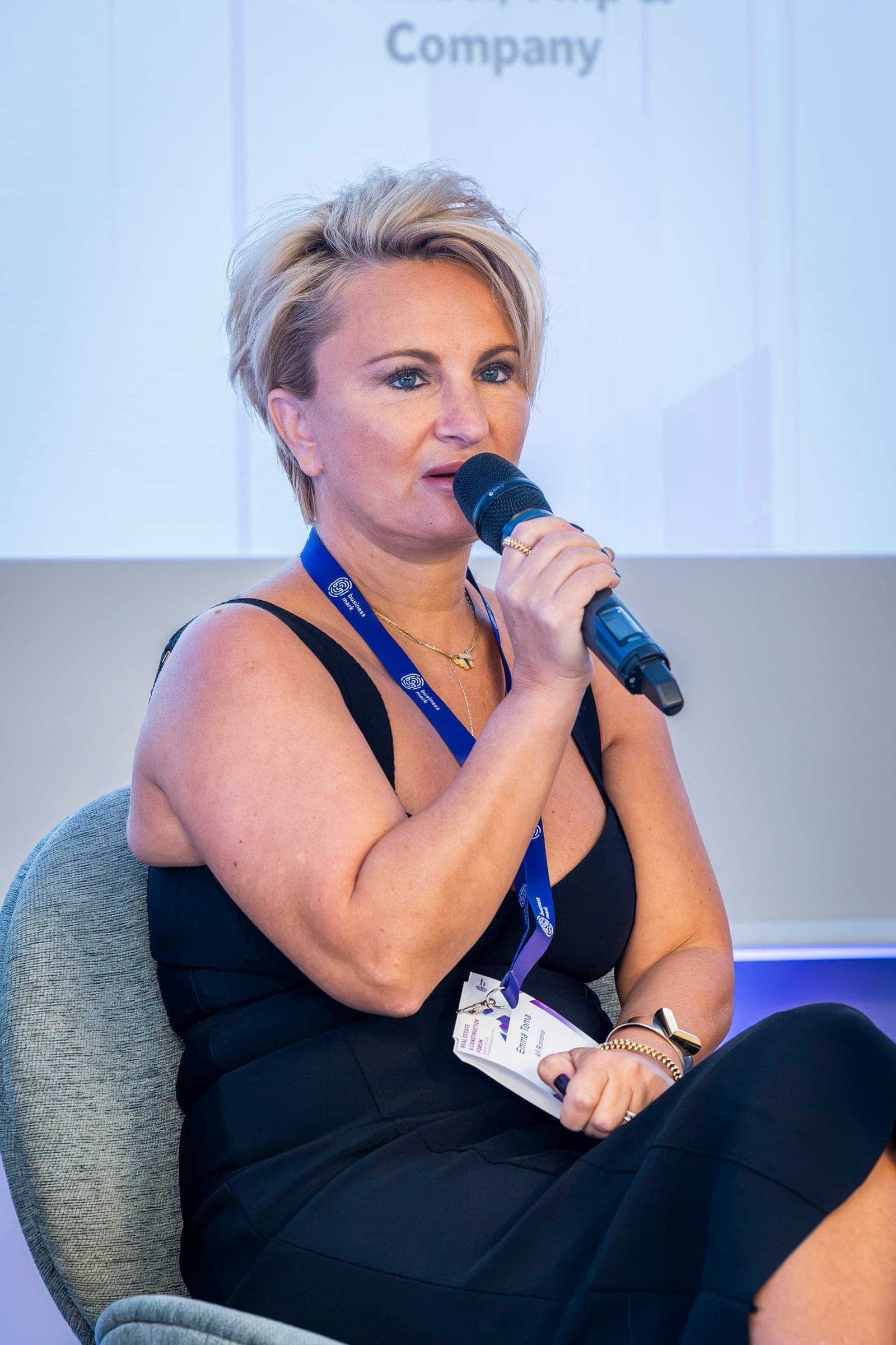 Emma Toma at the microphone, in a black dress