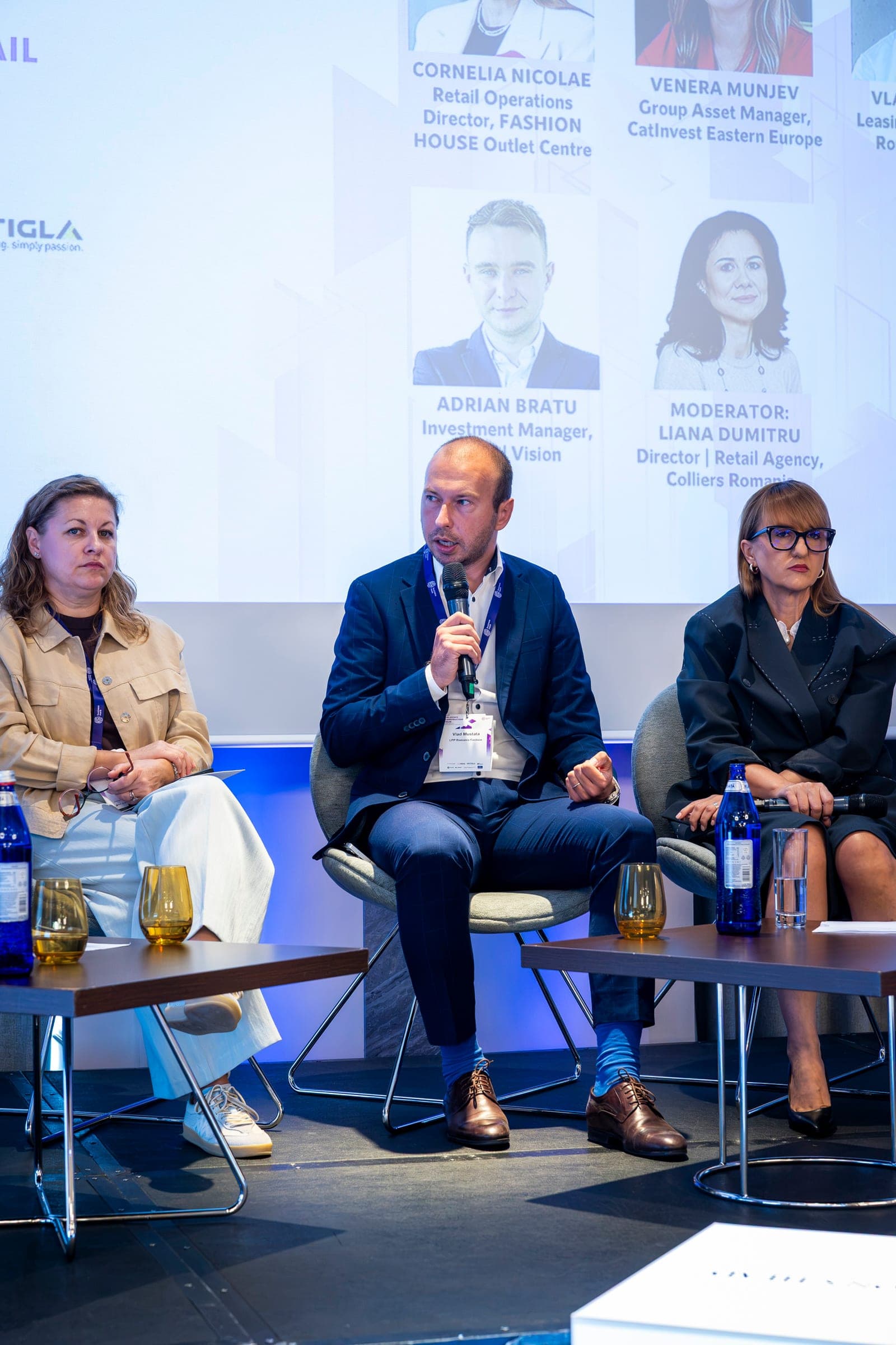 The retail panel on stage at the JW Marriott, the screen behind showing the speakers' names