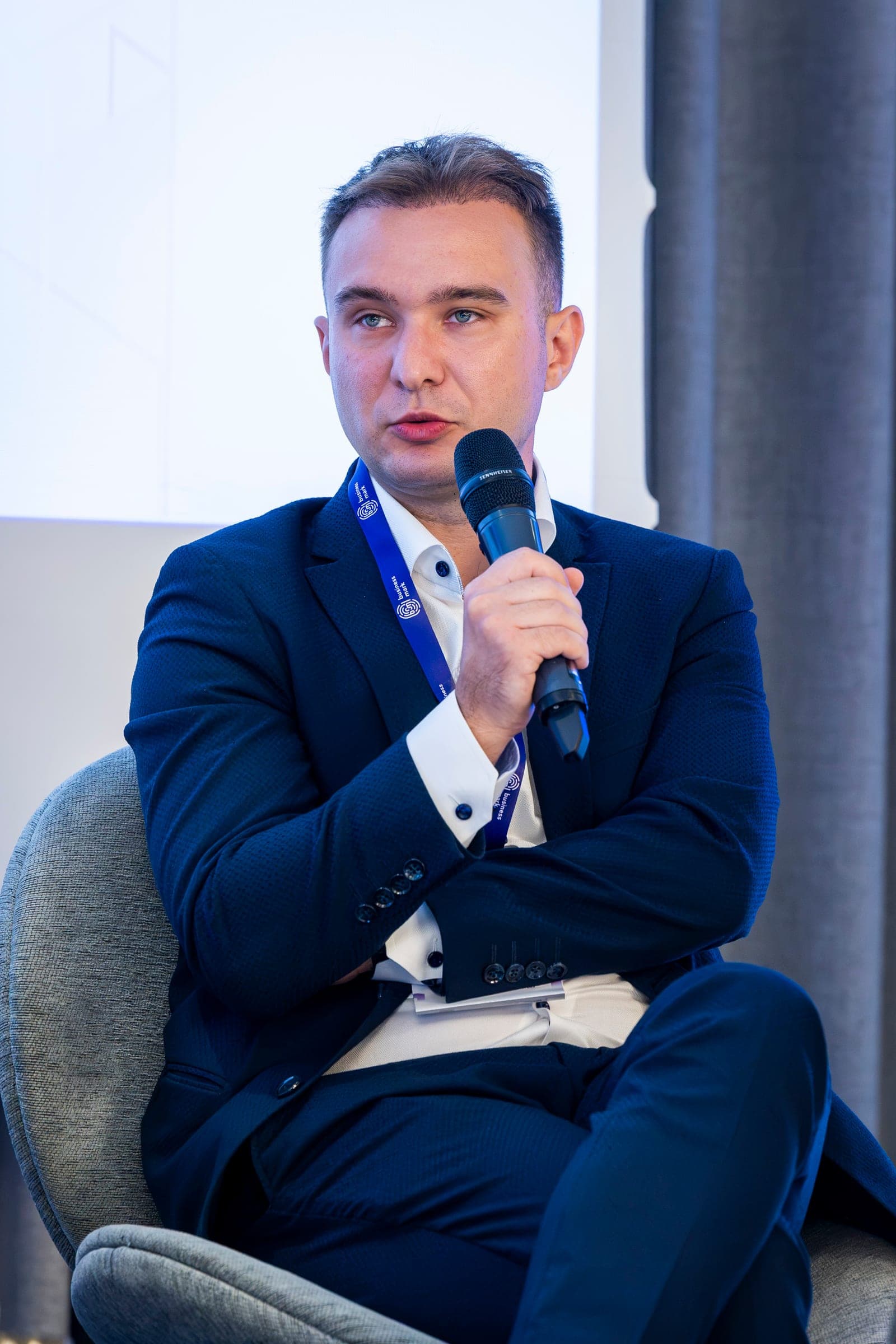 Adrian Bratu mikrofonnál, sötétkék öltönyben