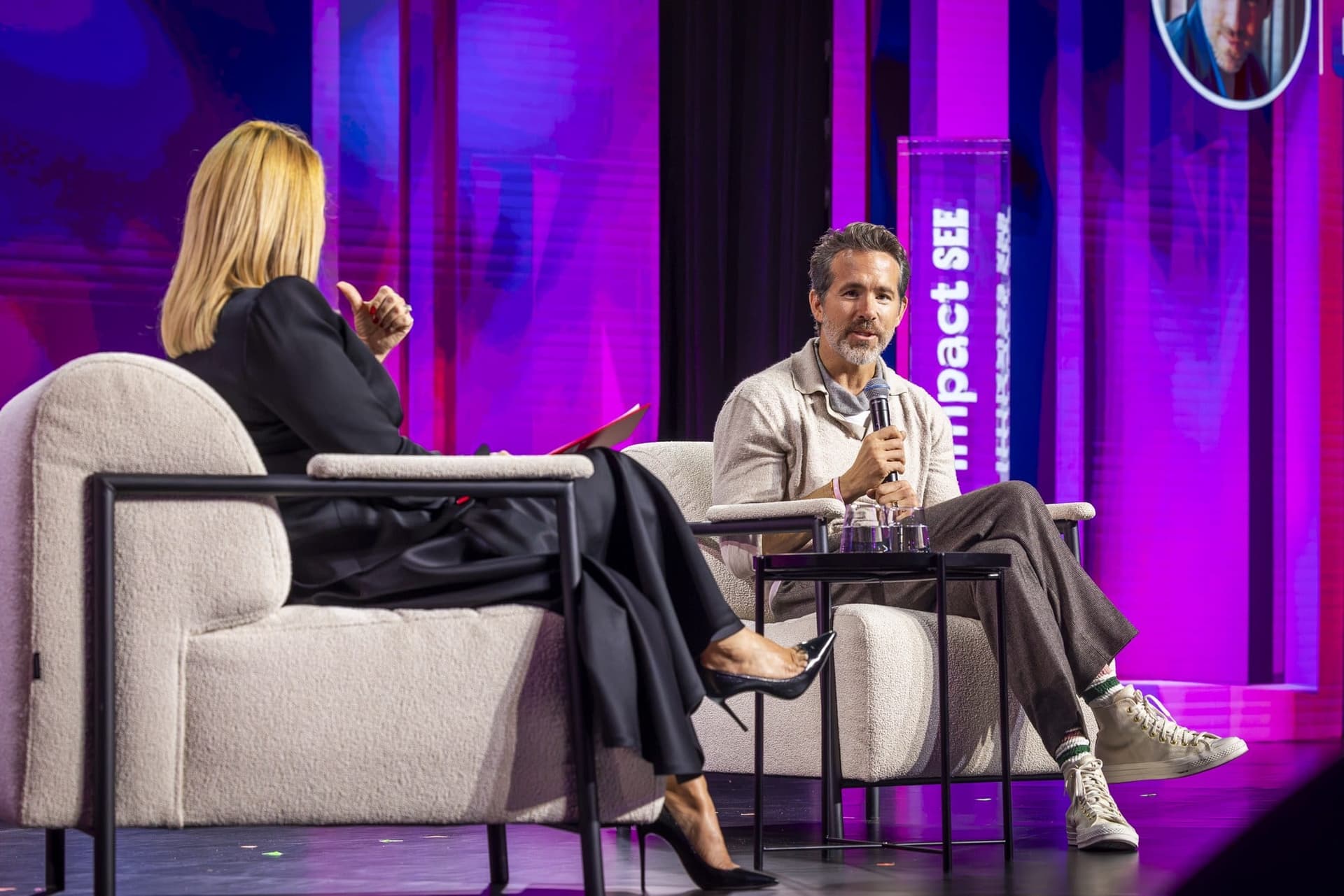 Ryan Reynolds în fotoliu, față în față cu Andreea Esca, văzută din spate, pe scena Impact SEE
