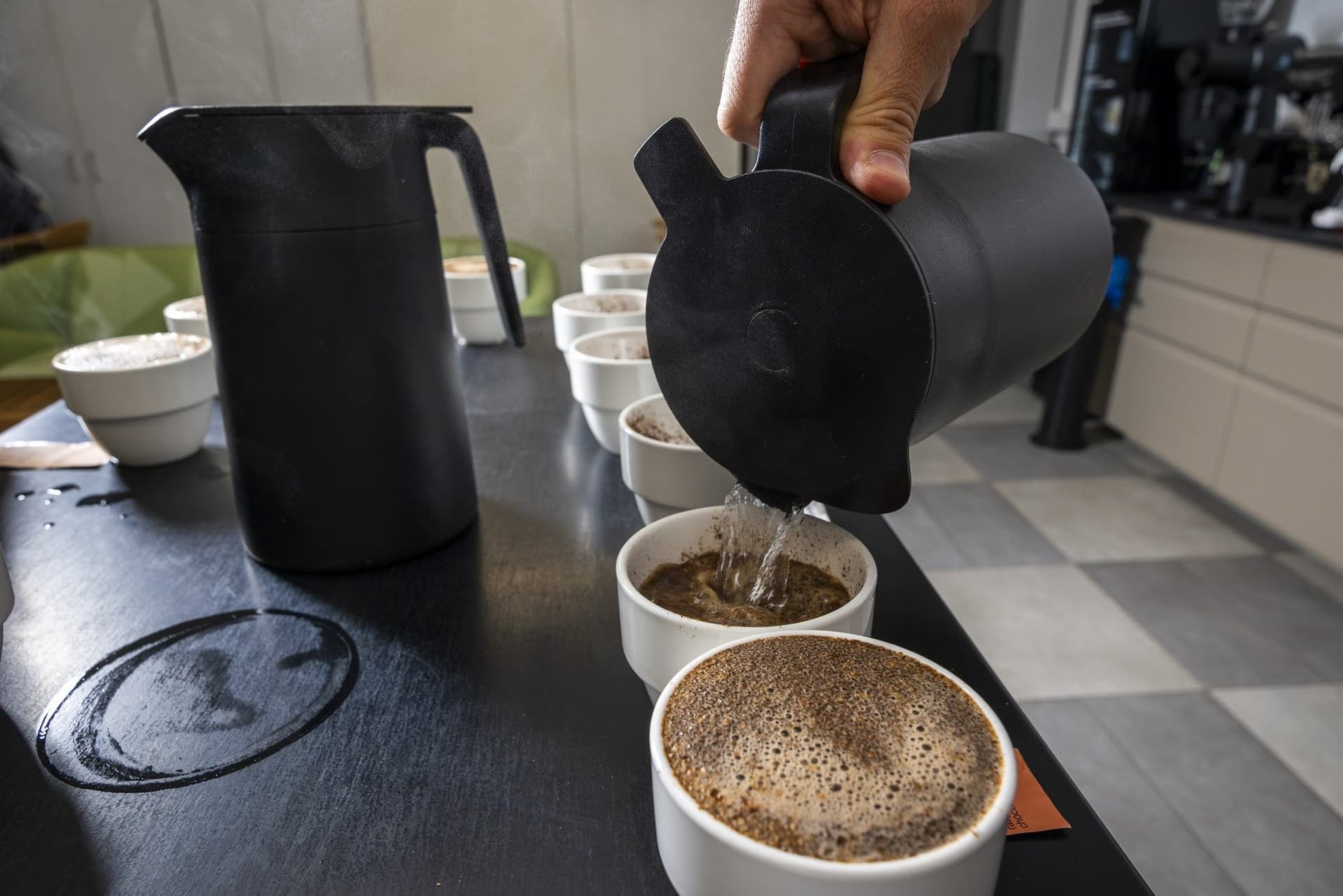 Apă fierbinte turnată peste cafeaua măcinată din ceștile de cupping