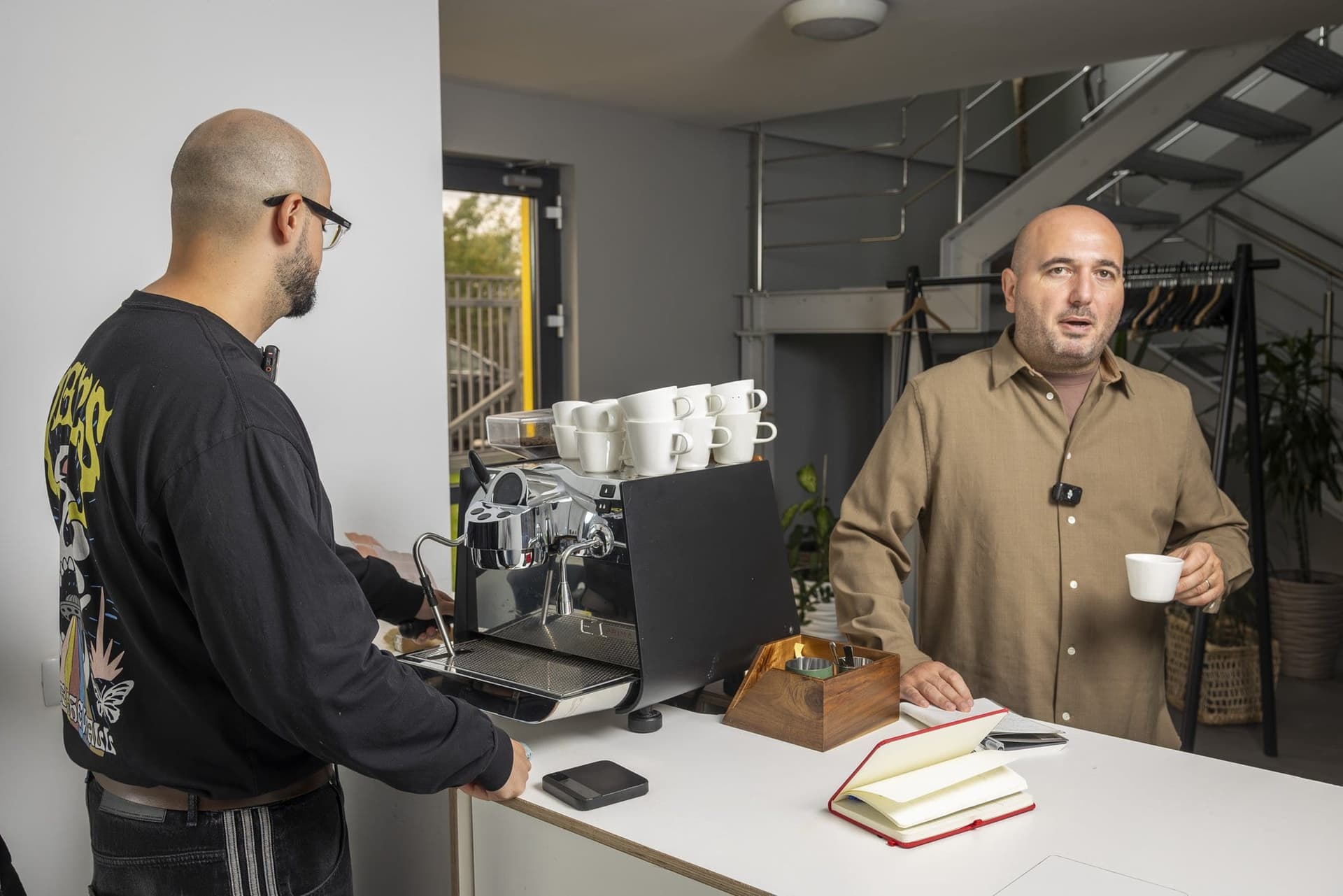 Mihai Panfil, cu o ceașcă de espresso în mână, lângă Mihai Grosu, aflat la espressor, în lobby-ul prăjitoriei