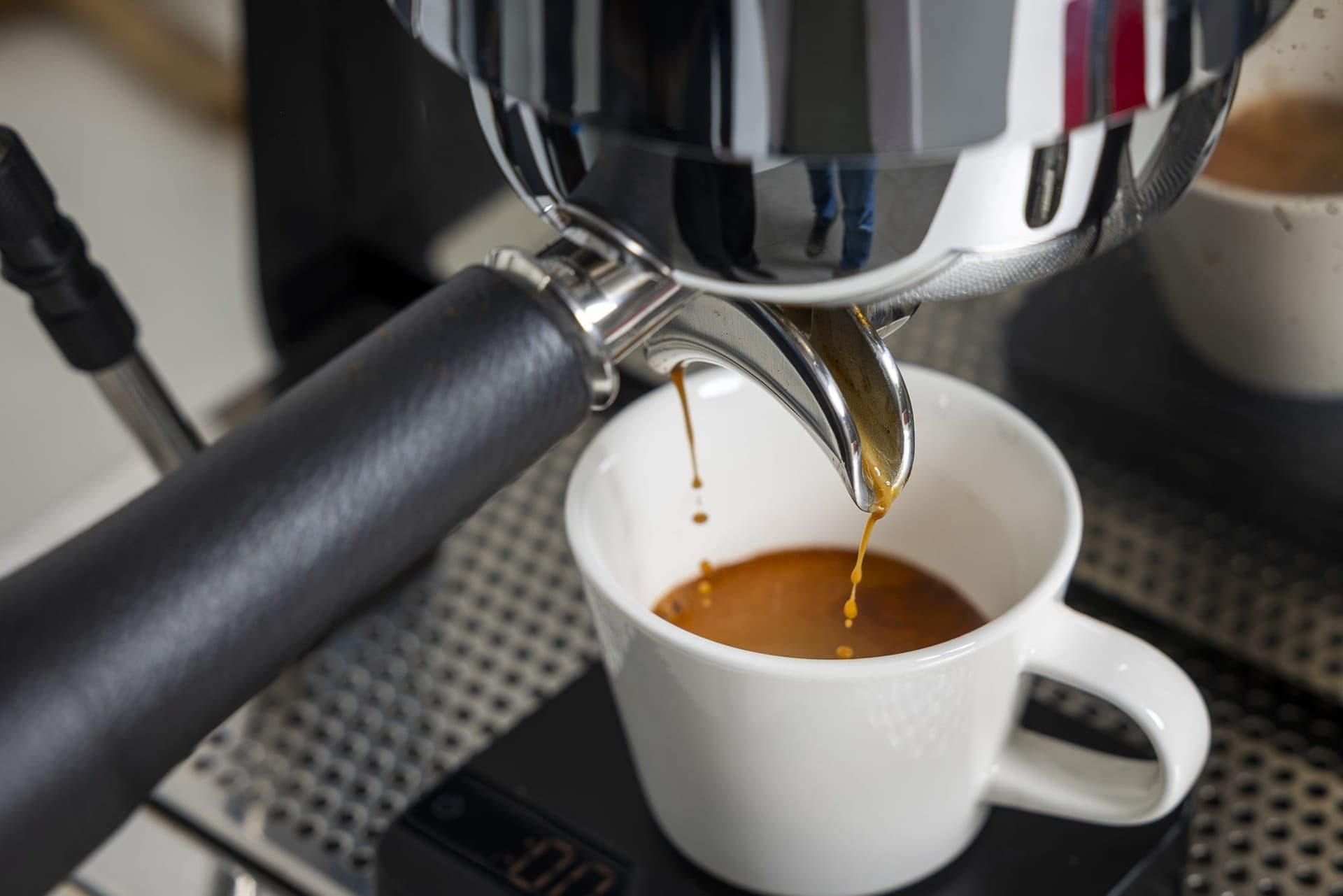 Espresso curgând din portafiltru într-o ceașcă albă
