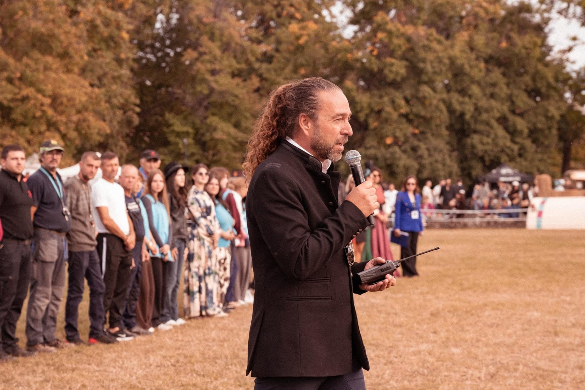 Mihnea Virgolici mikrofonba beszél egy hosszú, vállvetve álló embersor előtt