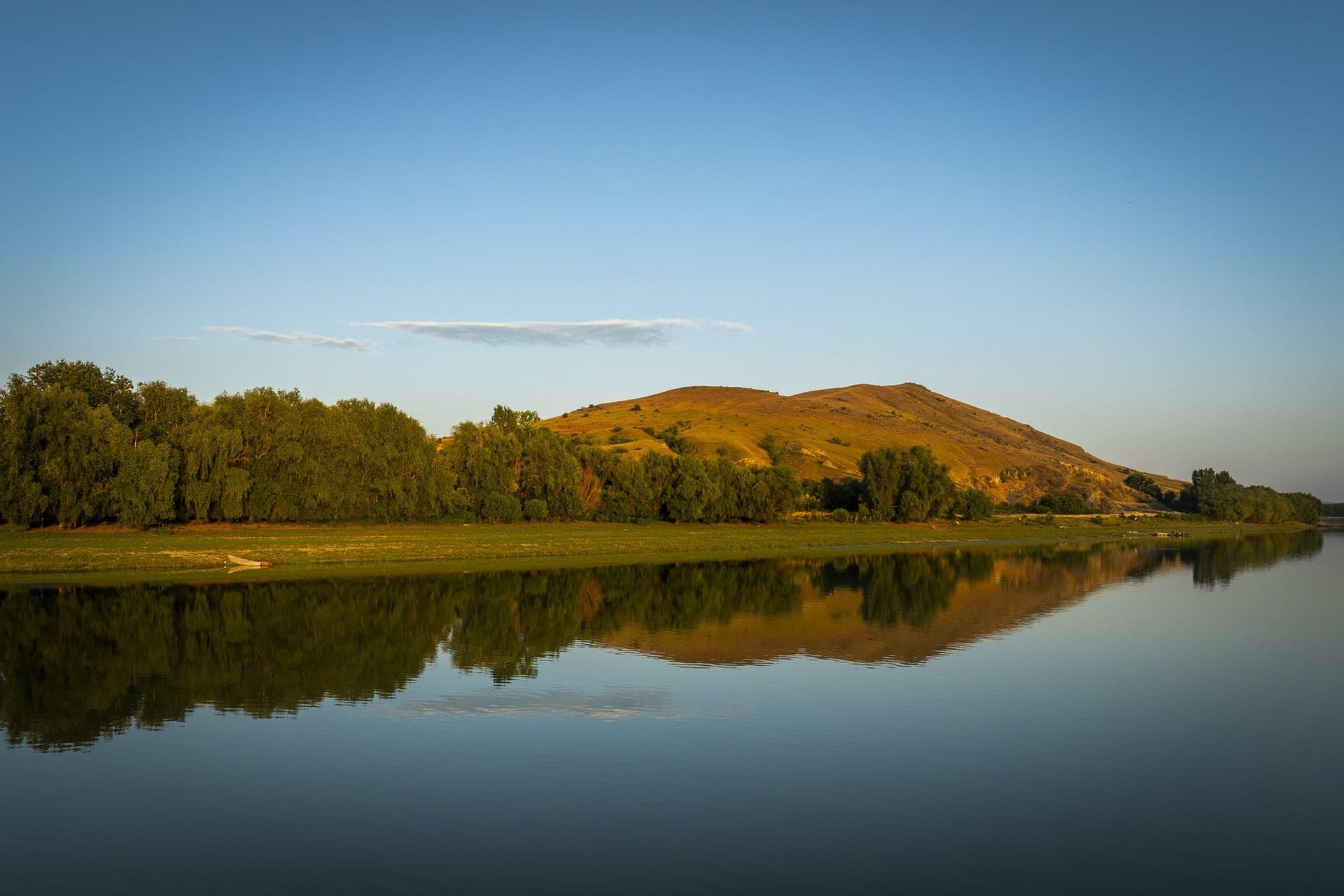 The Măcin branch of the Danube, with the hill reflected in the still water