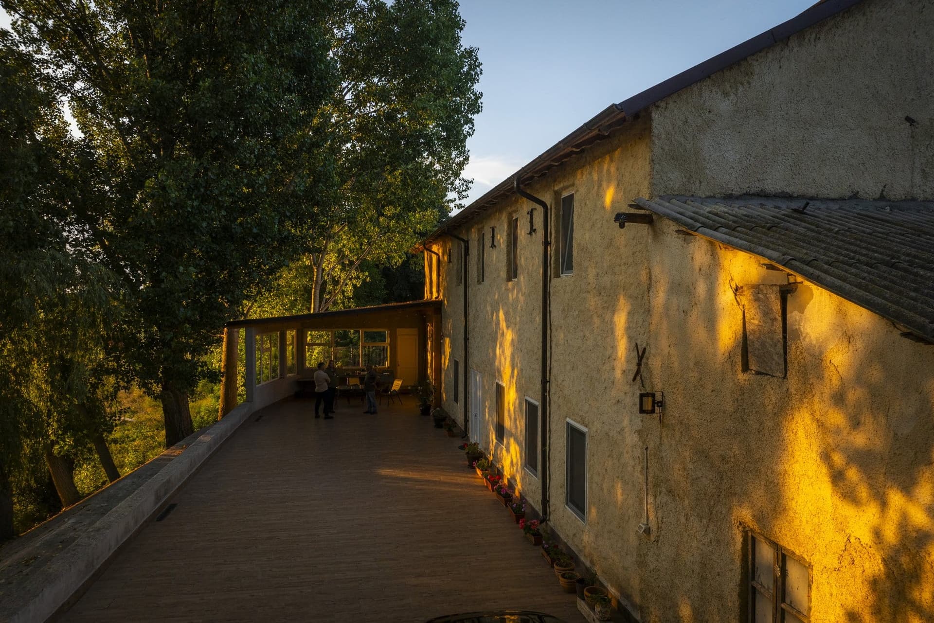 The facade of the building on the high bank in Peceneaga in the evening light, with iron anchors visible in the plaster