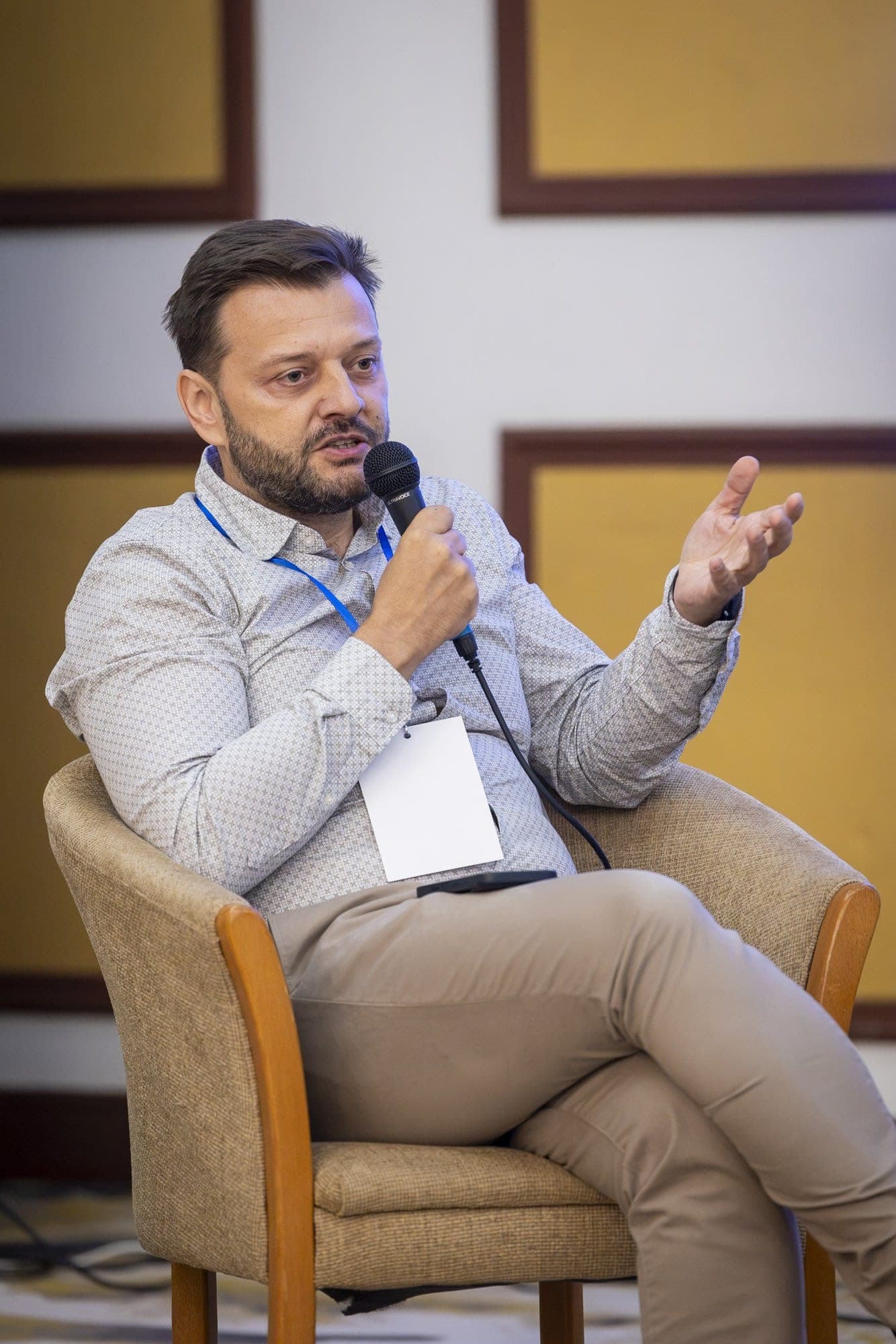 Marius Dragomiroiu vorbește la microfon, așezat în fotoliu, la IndustryShift Conference 2026