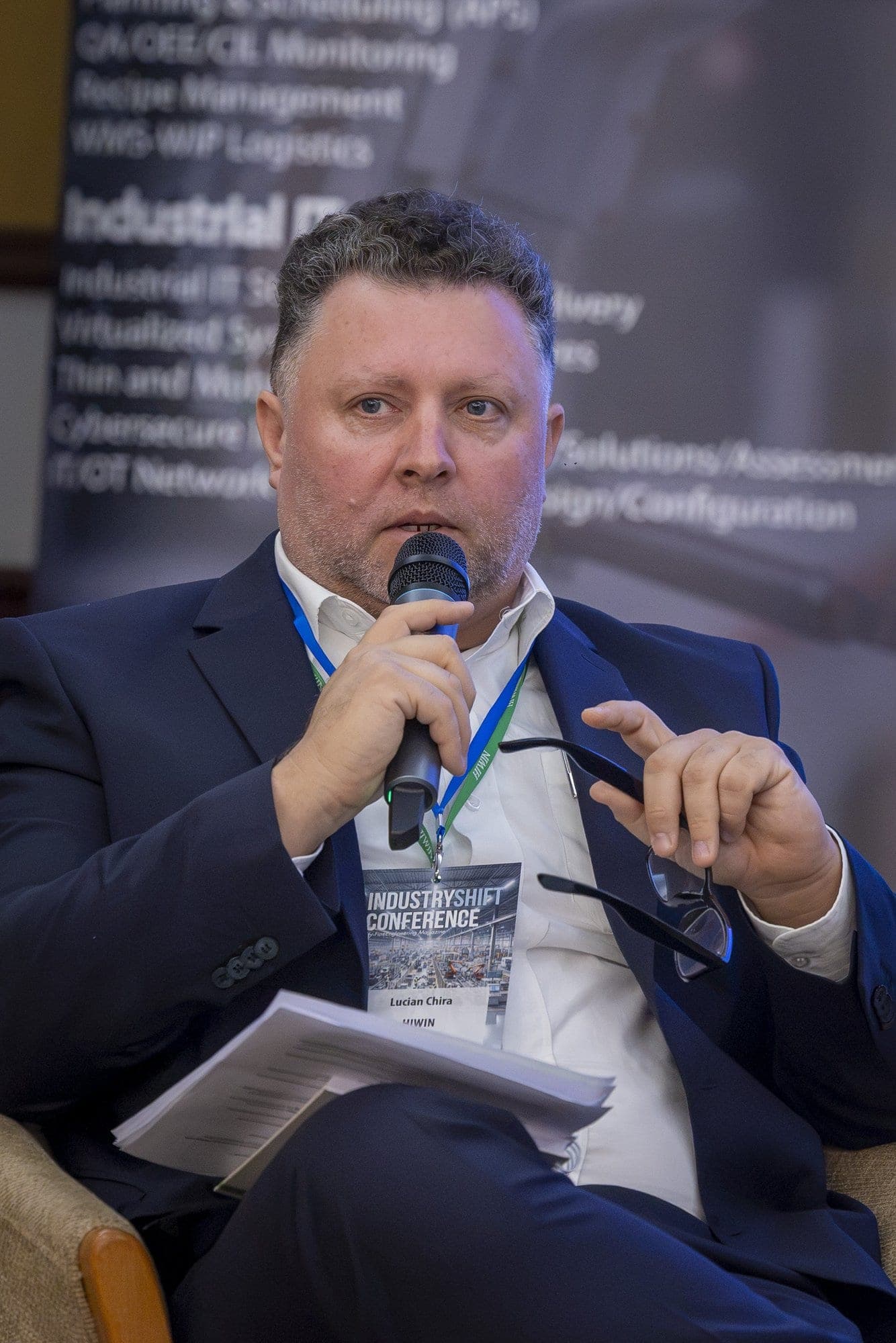 Lucian Chira, de la HIWIN, vorbește la microfon, cu foile de notițe pe genunchi