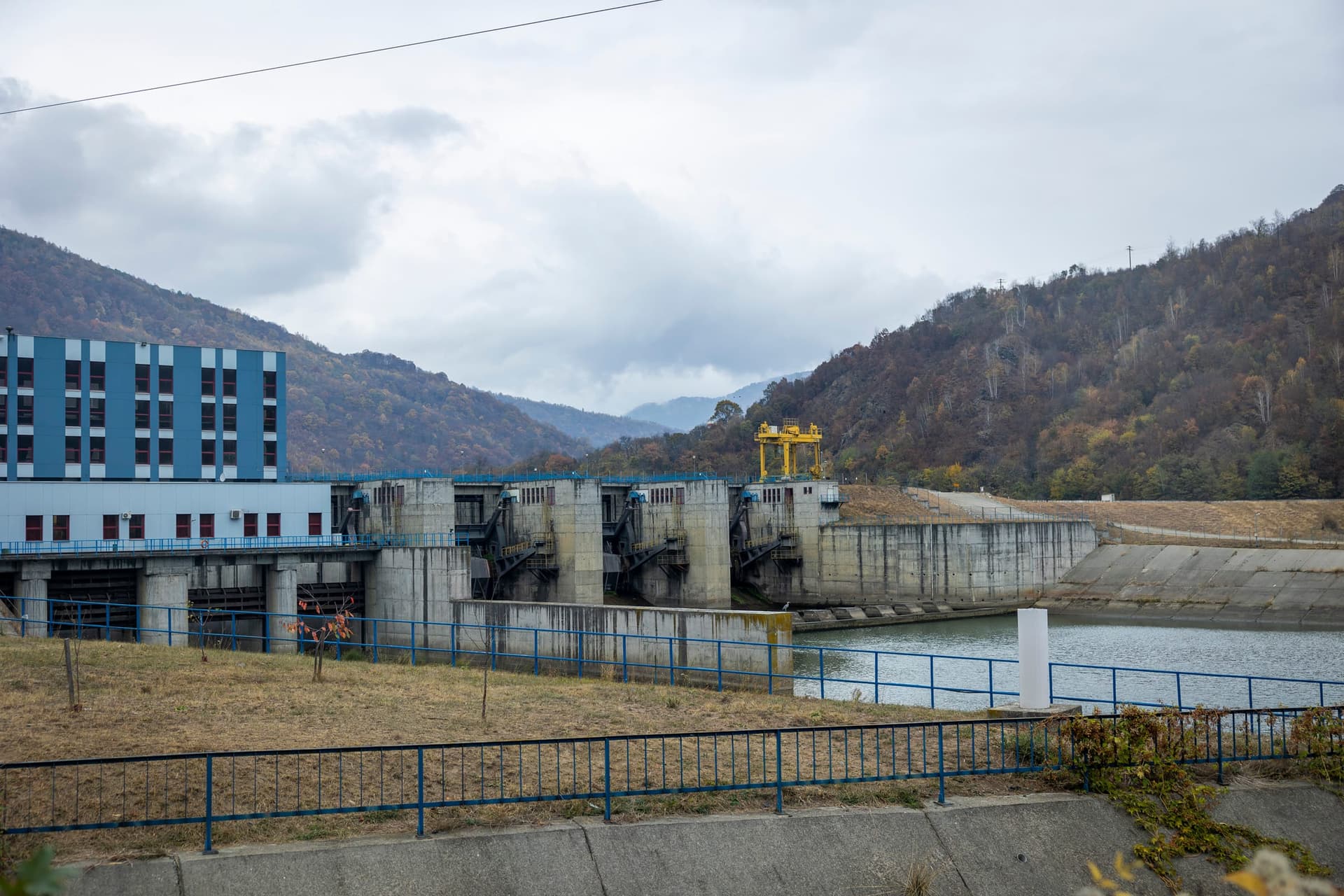 Barajul hidrocentralei Robești cu stavilele, văzut de la sol, cu apa Oltului în aval